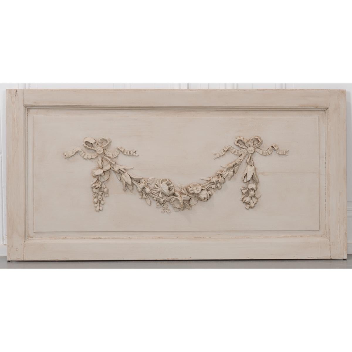 A fantastic carved panel, taken from a French 19th century painted boiserie collection. This wonderful panel depicts a floral garland swag that is laden with beautifully detailed roses, daffodils, lilies and their foliage suspended in air by