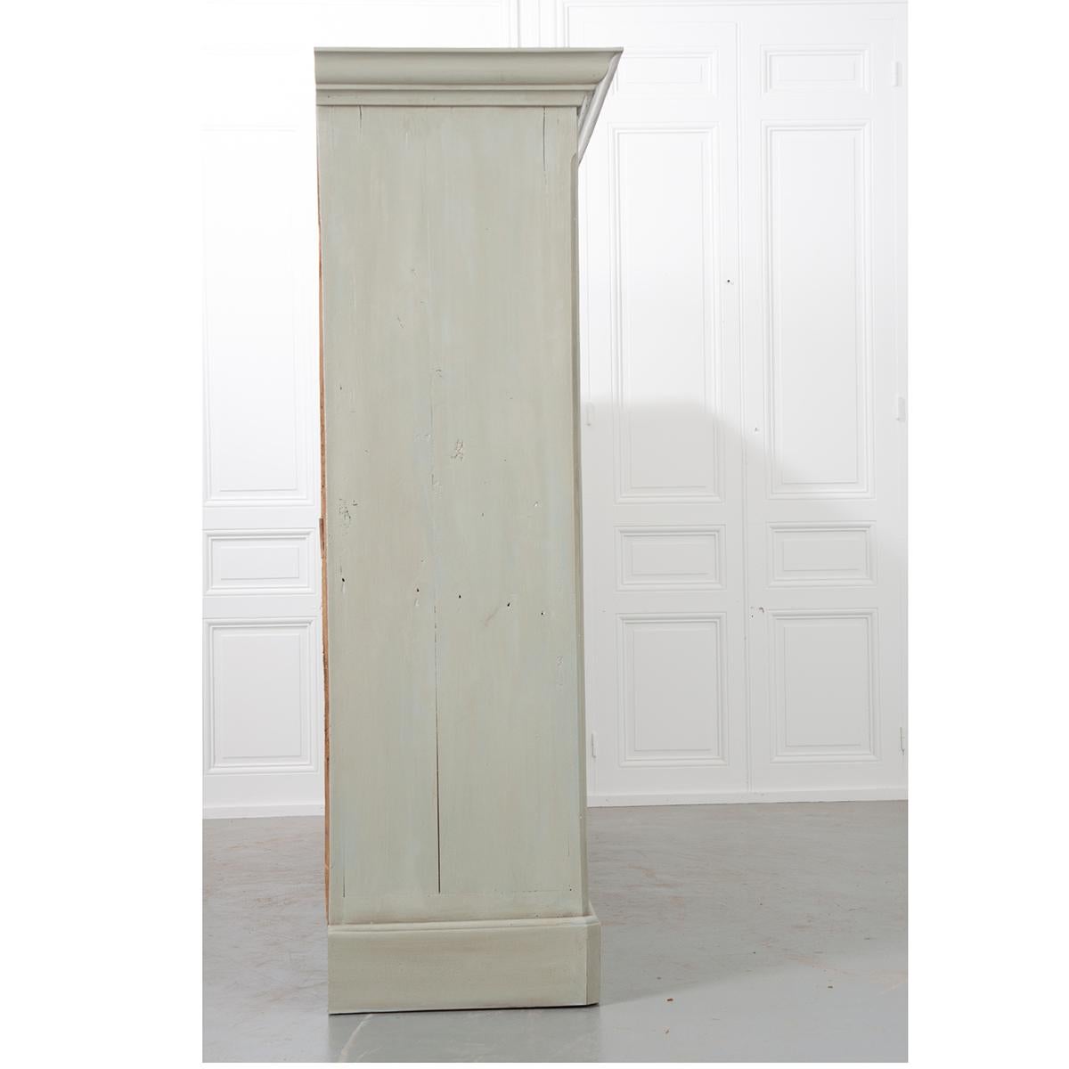 This freshly painted wardrobe cabinet is large and has ample storage. It is a green/grey color with a lighter coordinating paint used on the inset door panels and its interior is an earthen terracotta color. There are four doors, each set with an