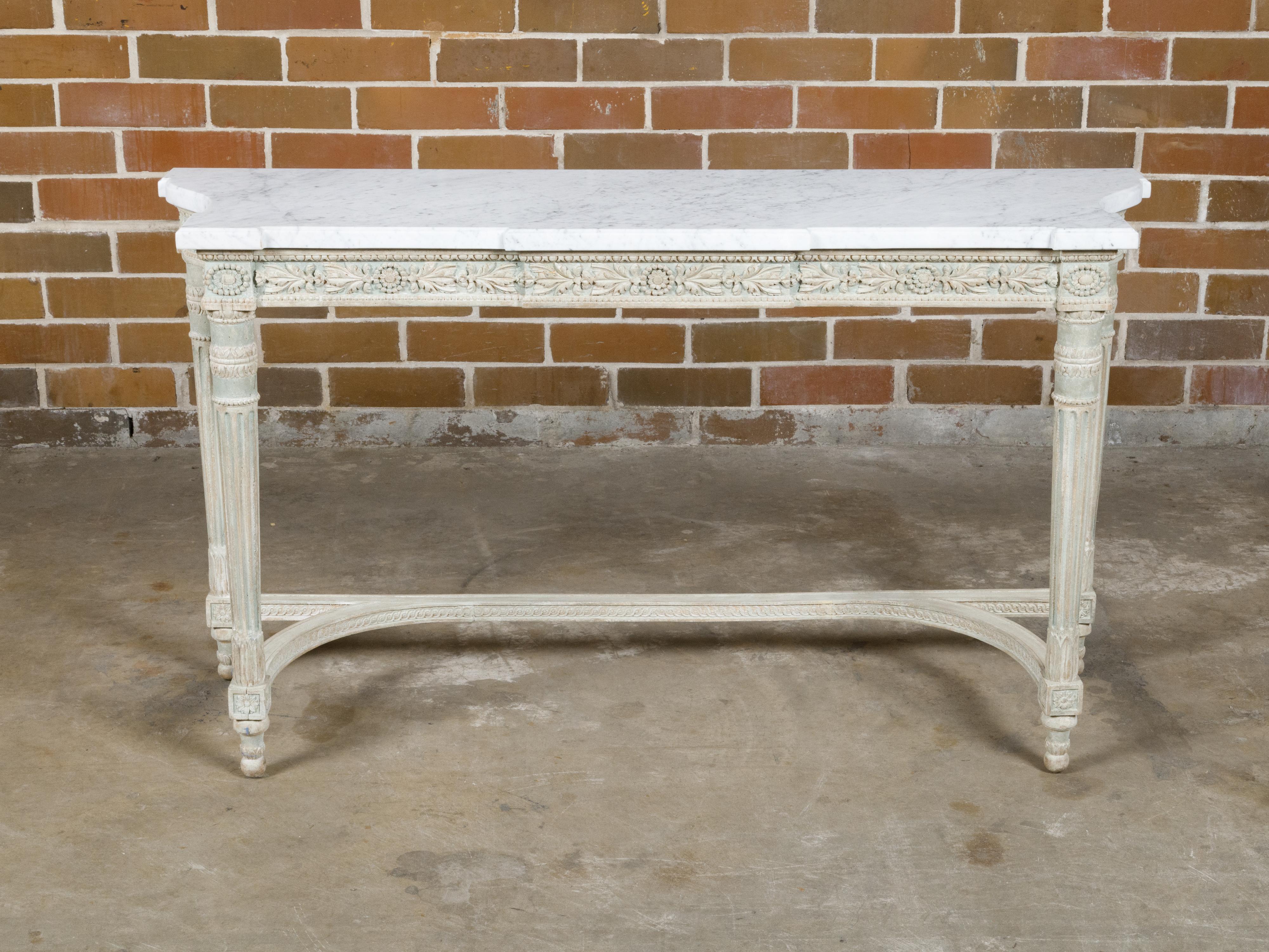 A French Neoclassical style painted console table from the 19th century with white veined marble top, carved apron and fluted legs. Immersed in the elegance of the French Neoclassical style, this 19th-century console table beautifully harmonizes