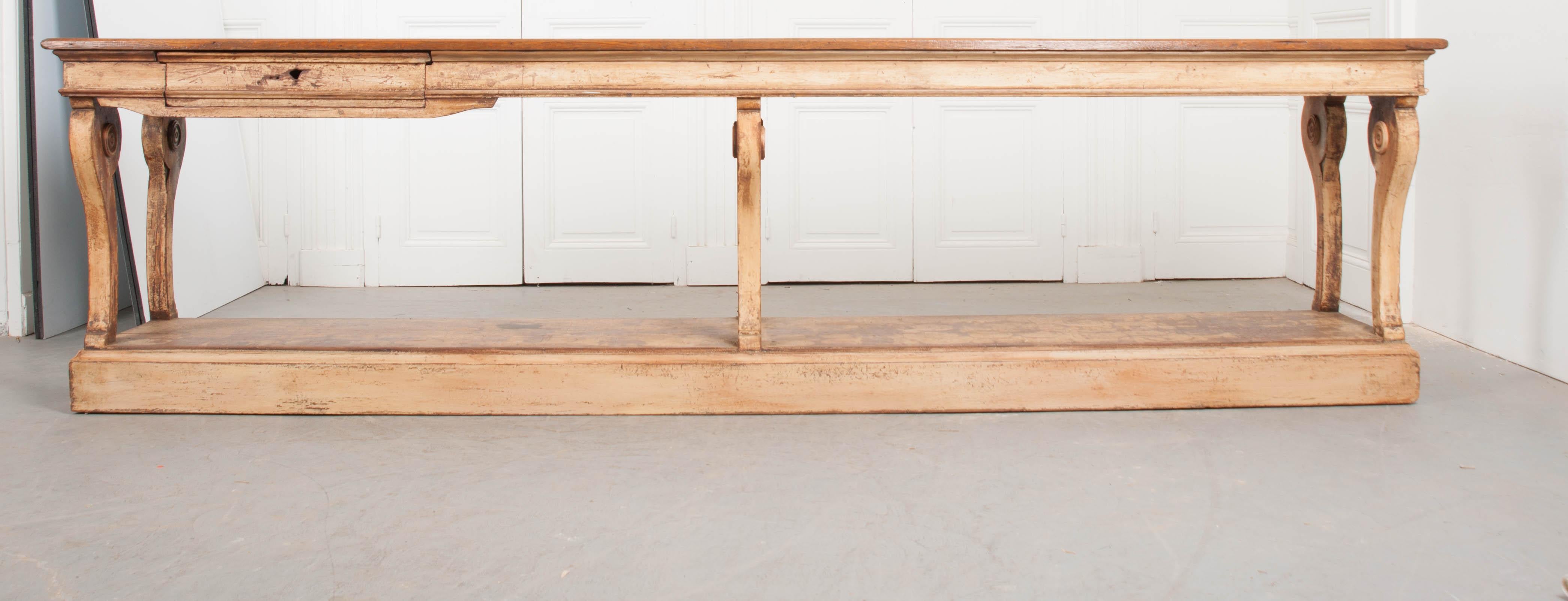 A gorgeous painted drapery table from 19th century, France. The lengthy table has a natural oak top set on a painted base. The base has been painted an ivory color that has acquired some antiquing along the way. The painted finish is exceptionally