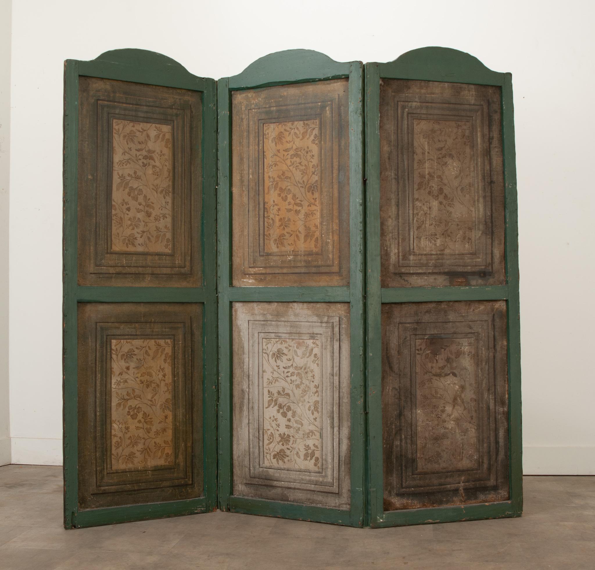 A French painted folding screen from the 19th Century. This antique folding screen features four tall panels with curved tops. On one side you’ll find painted floral designs on simple canvas panels, on the other side you’ll find a painted canvas