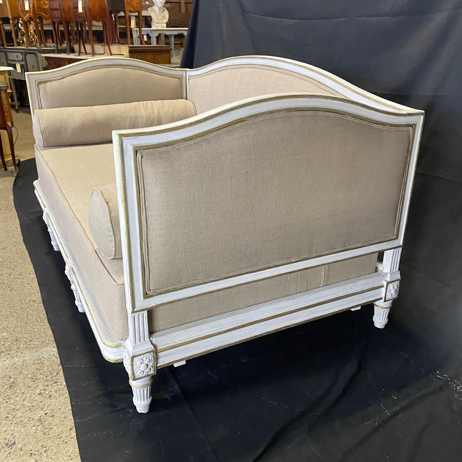 A fantastic Louis XVI restored daybed from France circa 1830’s. The ivory painted frame with gold gilt molding has a wonderful patina. Newly reupholstered in a neutral high quality grayish beige material, the daybed has two bolsters at either end.