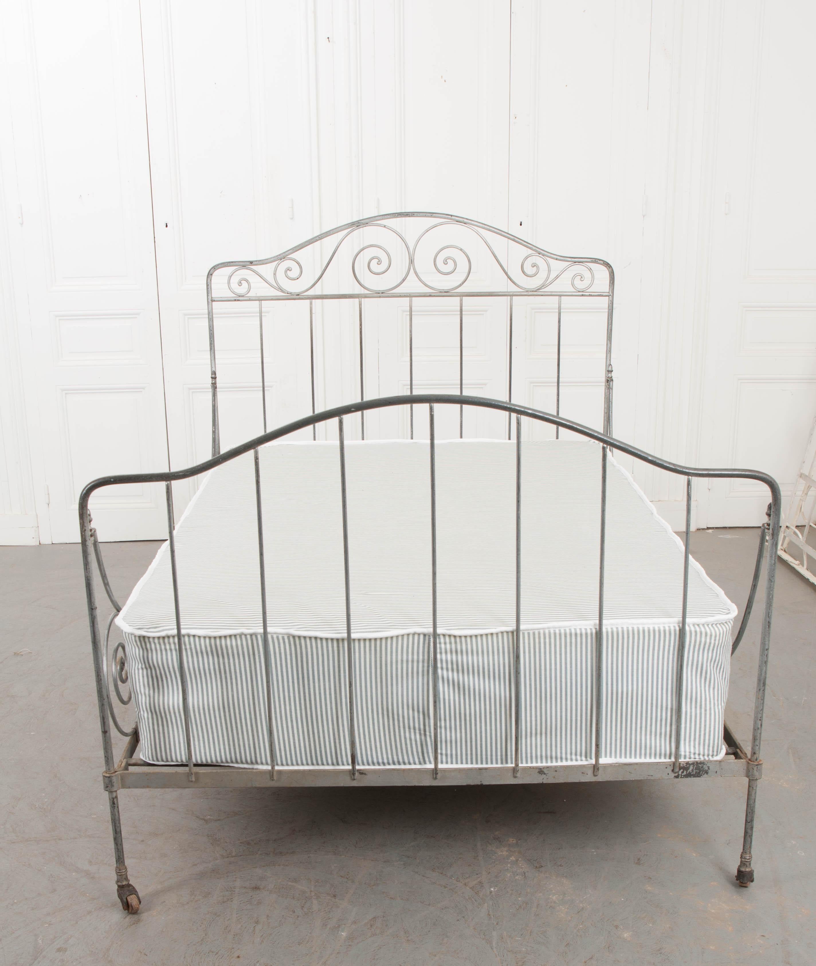 This lovely full-size folding silver-painted and gold-highlighted iron Campaign daybed, c. 1870, was found in France. Originally created for military campaigns, it was made to fold for ease of travel. The shaped headboard features a scroll-work