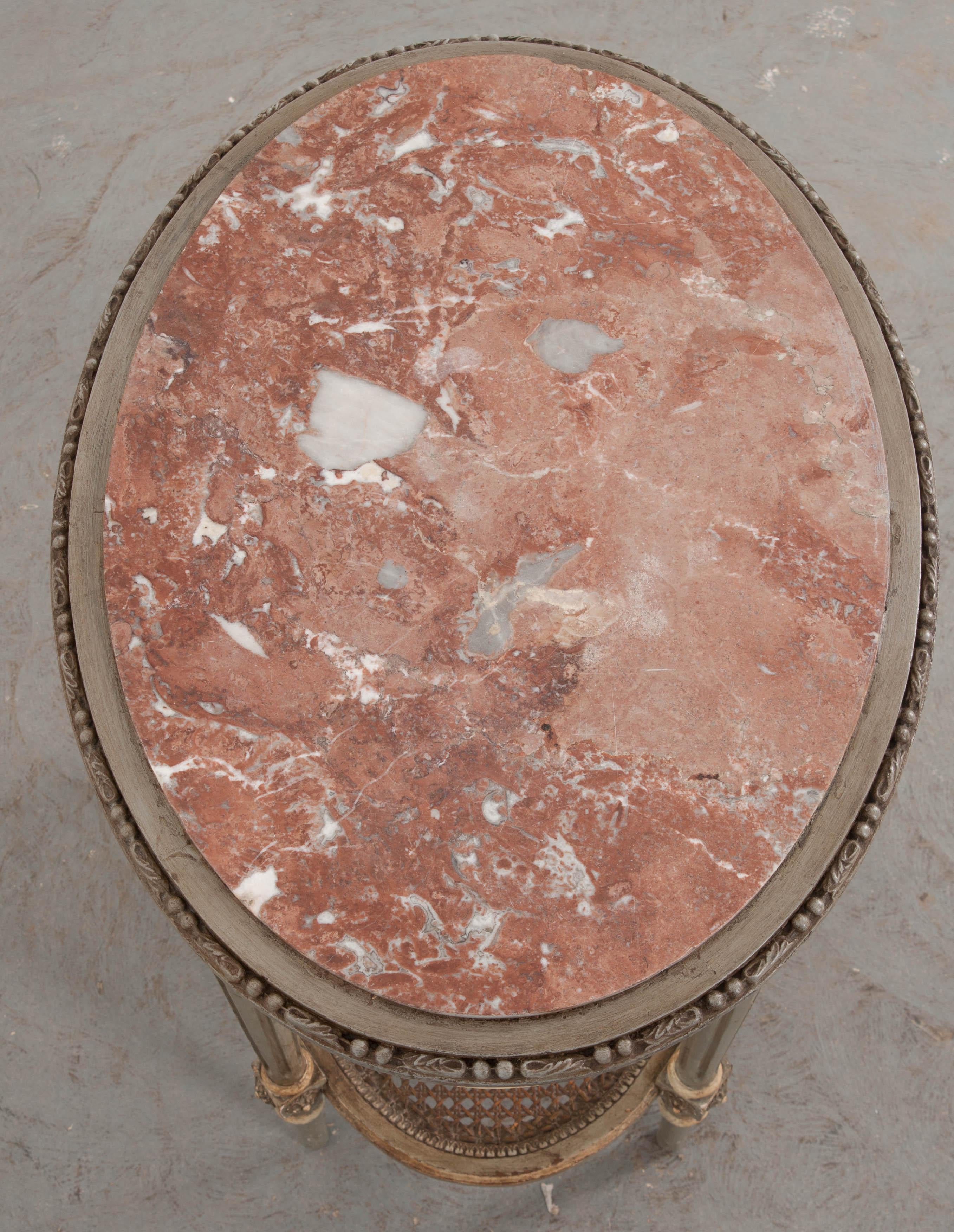 A delightfully charming Louis XVI painted marble top oval side table from 19th century France. Secured by a perimeter of beaded leaf moulding, the red marble top is set into this fabulous oval table, and is in excellent antique condition, with grey