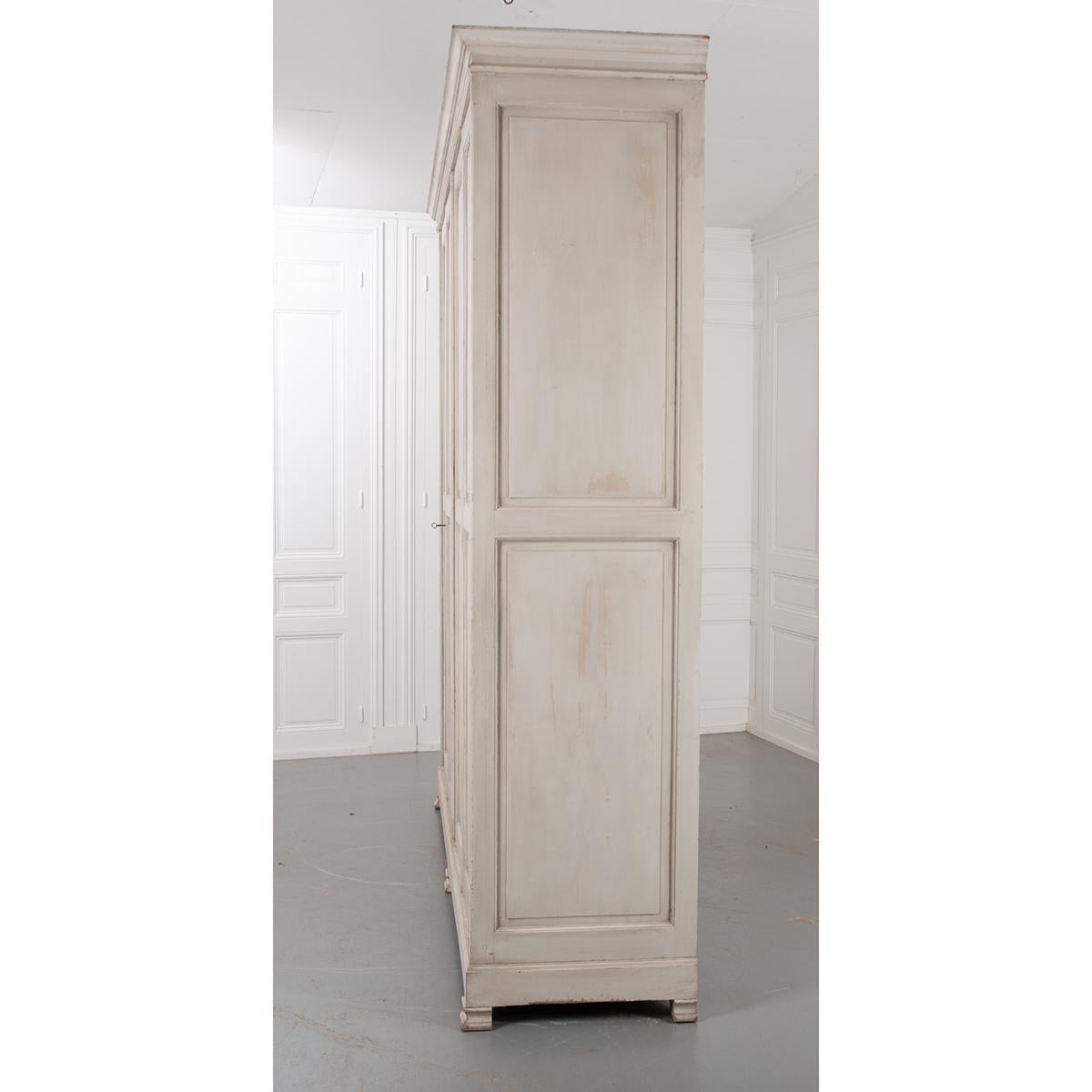 This is a wonderful four door French 19th century painted pine wardrobe. It is painted in an appealing soft, more recent, gray-green finish. The piece has nice simple straight lines with a cornice across the top of the piece. It has three bracket