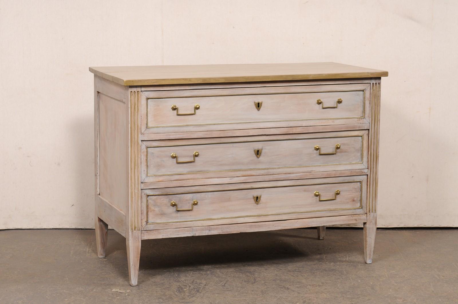 Una commode francese in legno dipinto, con ferramenta e accenti in ottone, risalente al XIX secolo. Questa antica cassapanca francese presenta un piano di forma rettangolare sopra una cassa che ospita tre cassetti a grandezza naturale, incorniciati