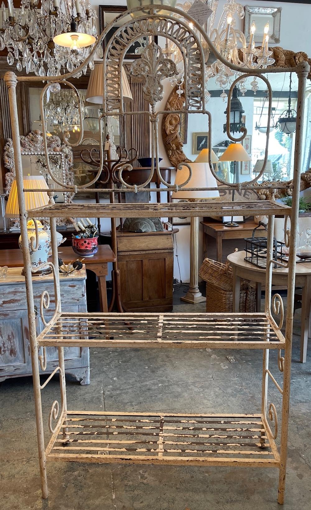 This is a very fine example of a wrought iron 19th century French bakers rack. The iron is shaped in many designs on the upper section with more designs on both sides. Though painted some of it has flaked away.