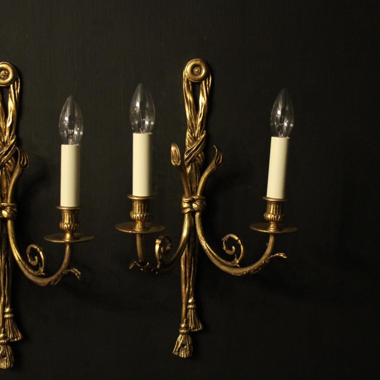 A good French pair of gilded bronze twin arm antique wall lights, the reeded leaf clad scrolling arms with circular bobeches drip pans and reeded candle sconces, issuing from an elongated tapering pierced rope and tassel backplate, lovely original