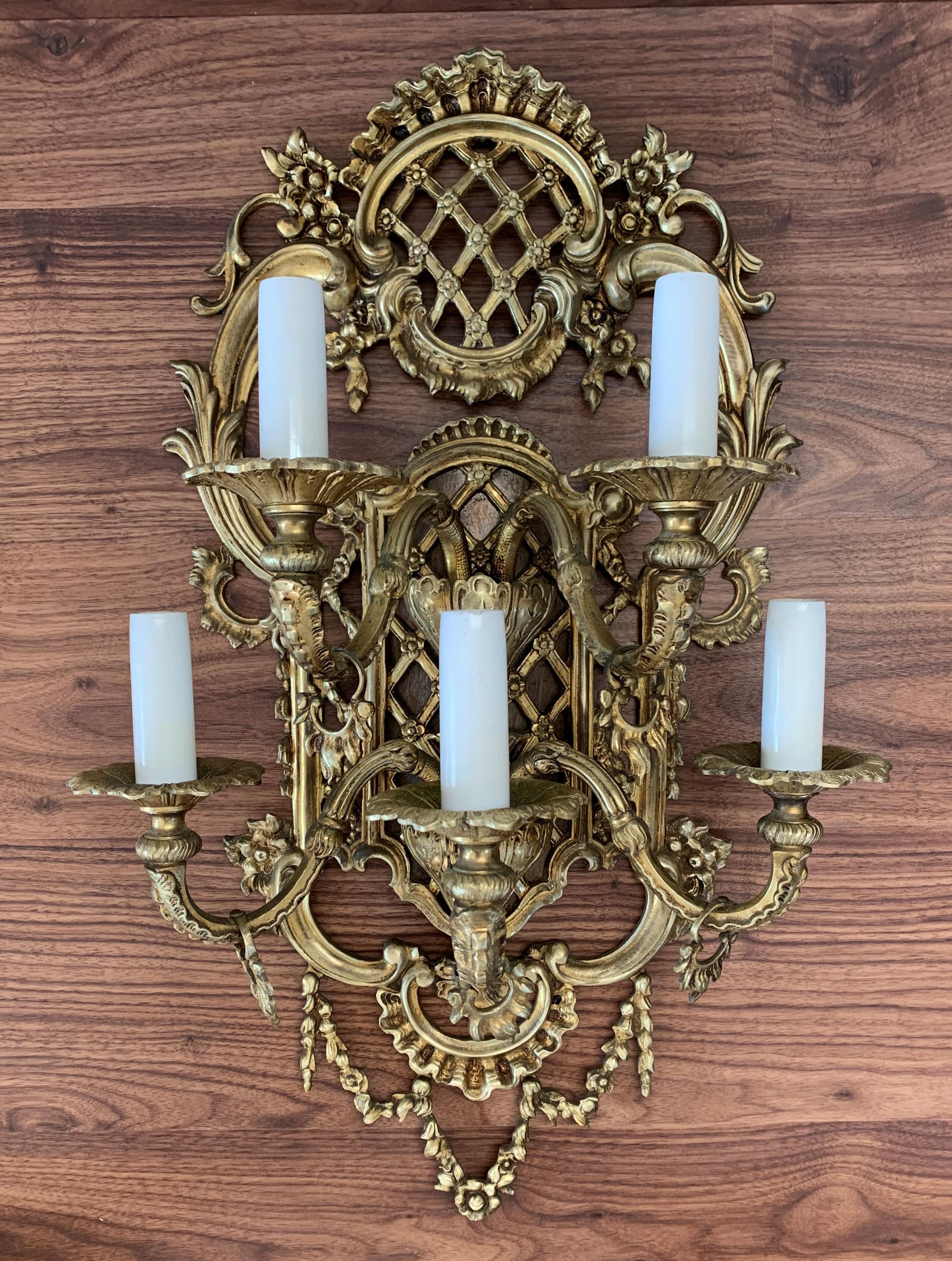 A large French pair of gilded bronze quintuple arm antique wall sconces, the ornate leaf scrolling arms with leaf bobeches drip pans, issuing from a decoratively cast elongated tapering leaf backplate with central cartouche, excellent original