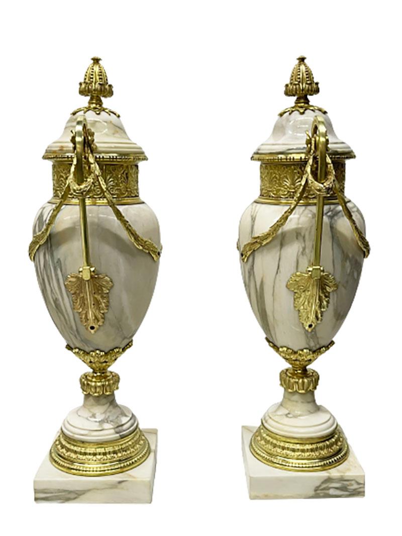 French 19th century pair of marble with ormolu vases

Bronze gilded marble in the shape of urns vases. The marble vases raised on a square marble base. The base with foliate rims with acanthus and floral motif. The curved ears decorated with leaf