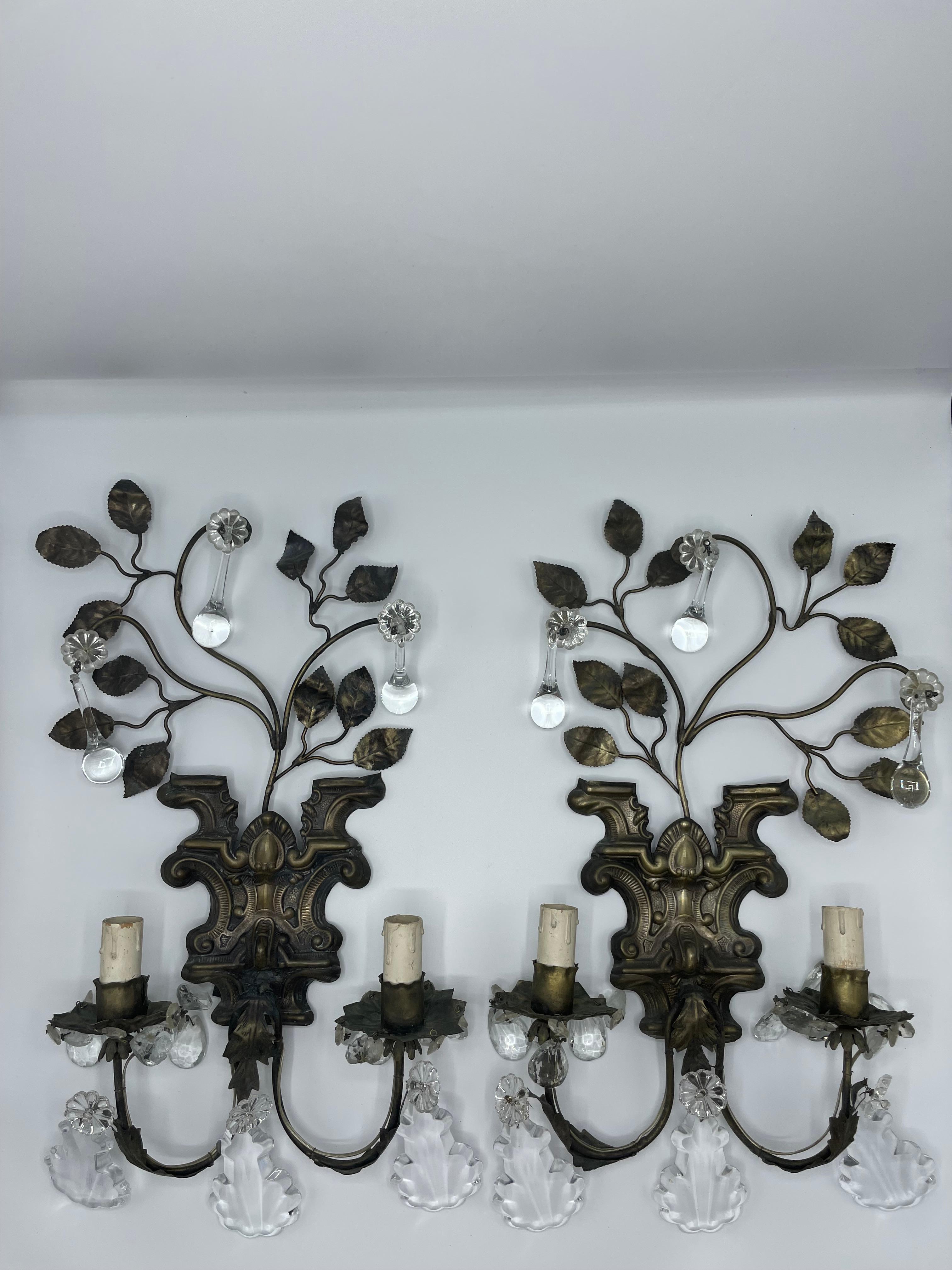 Paire d'appliques françaises en tole repoussée de la fin du 19ème siècle, à deux lumières.
Des branches au feuillage taillé sont fixées à un socle orné de reliefs décoratifs. Des glands en forme de goutte d'eau pendent des feuilles minces. Deux