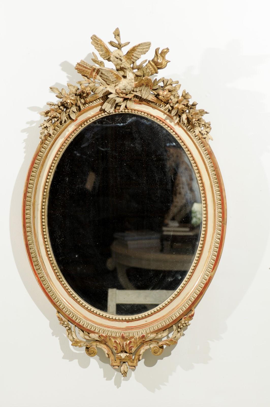 A French oval painted and parcel gilt marriage mirror from the 19th century, with carved crest and kissing doves. Featuring an oval shape, this exquisite French wall mirror exudes a romanticism particularly appropriate for a marriage piece. Our eye