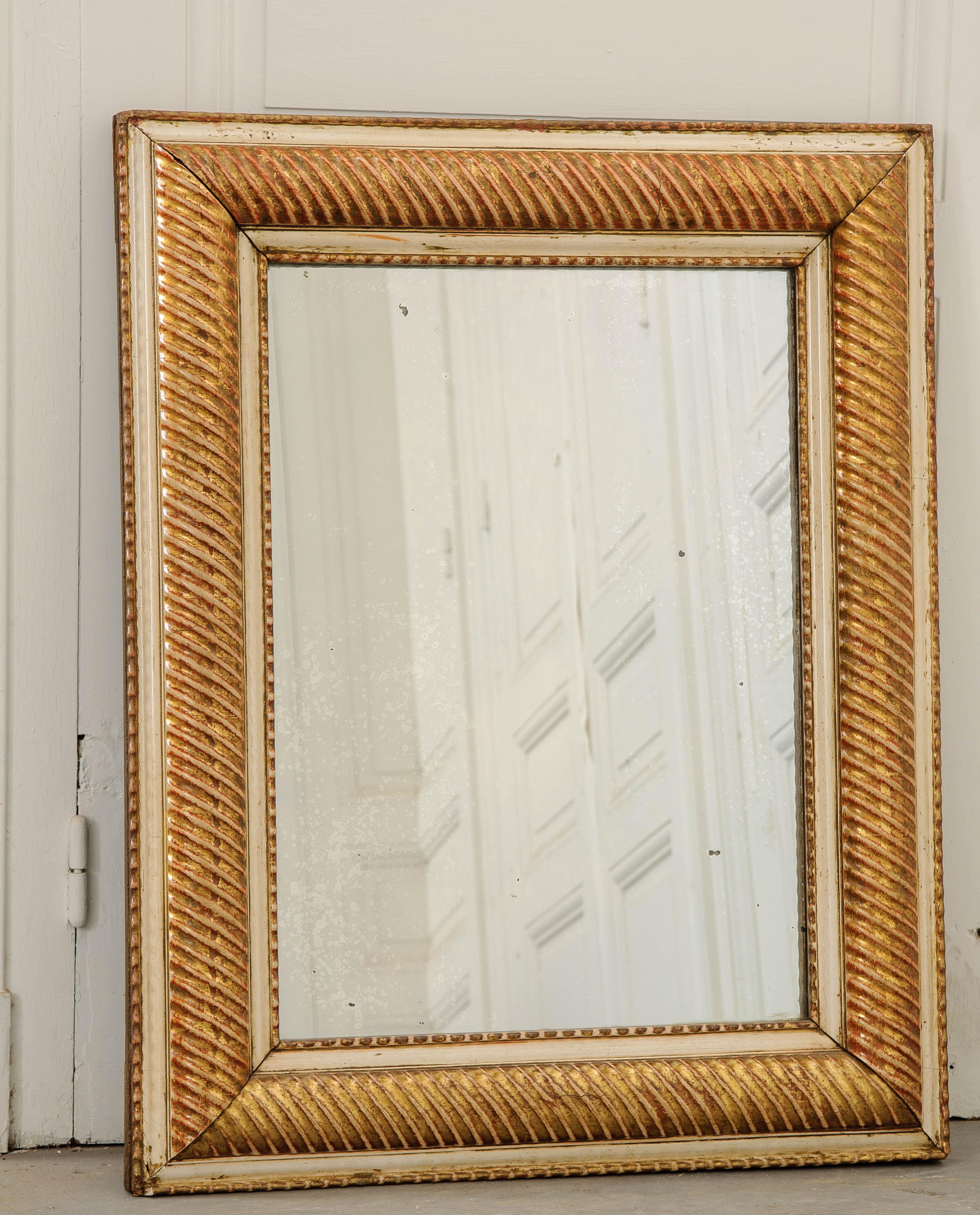 Un joli miroir en bois doré, fabriqué en France, vers 1850. Ce miroir ancien rectiligne possède un cadre épais avec un design unique qui l'encercle entièrement. Le cadre a été conçu avec un motif en tire-bouchon qui voit des nervures orientées en