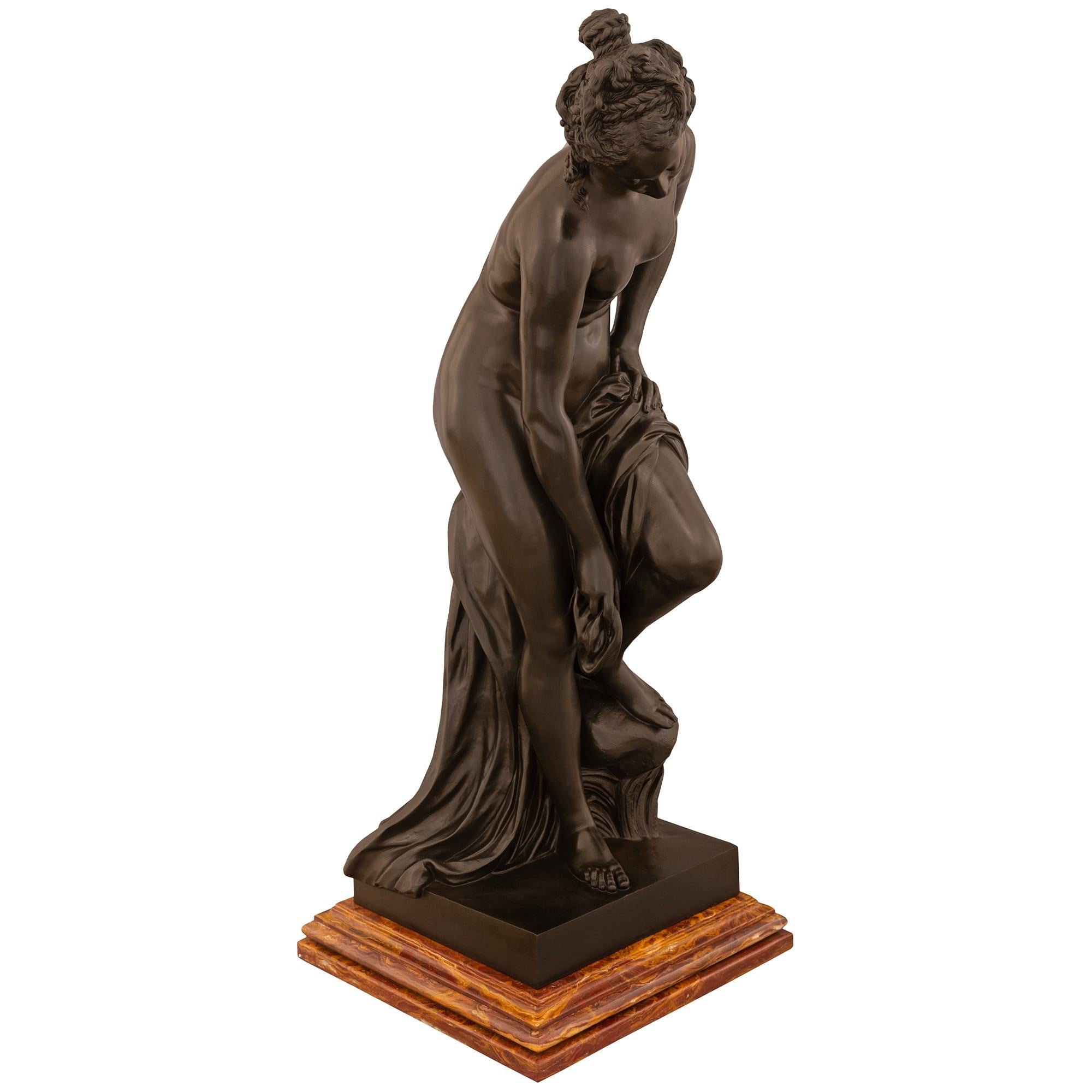 Una grande statua in bronzo patinato e marmo di Venere al Bagno del XIX secolo. La Venere è sollevata da una bella base in marmo Sanguine Oran Cipolin screziato e tiene una veste drappeggiata con la gamba sinistra su una roccia mentre le dita dei