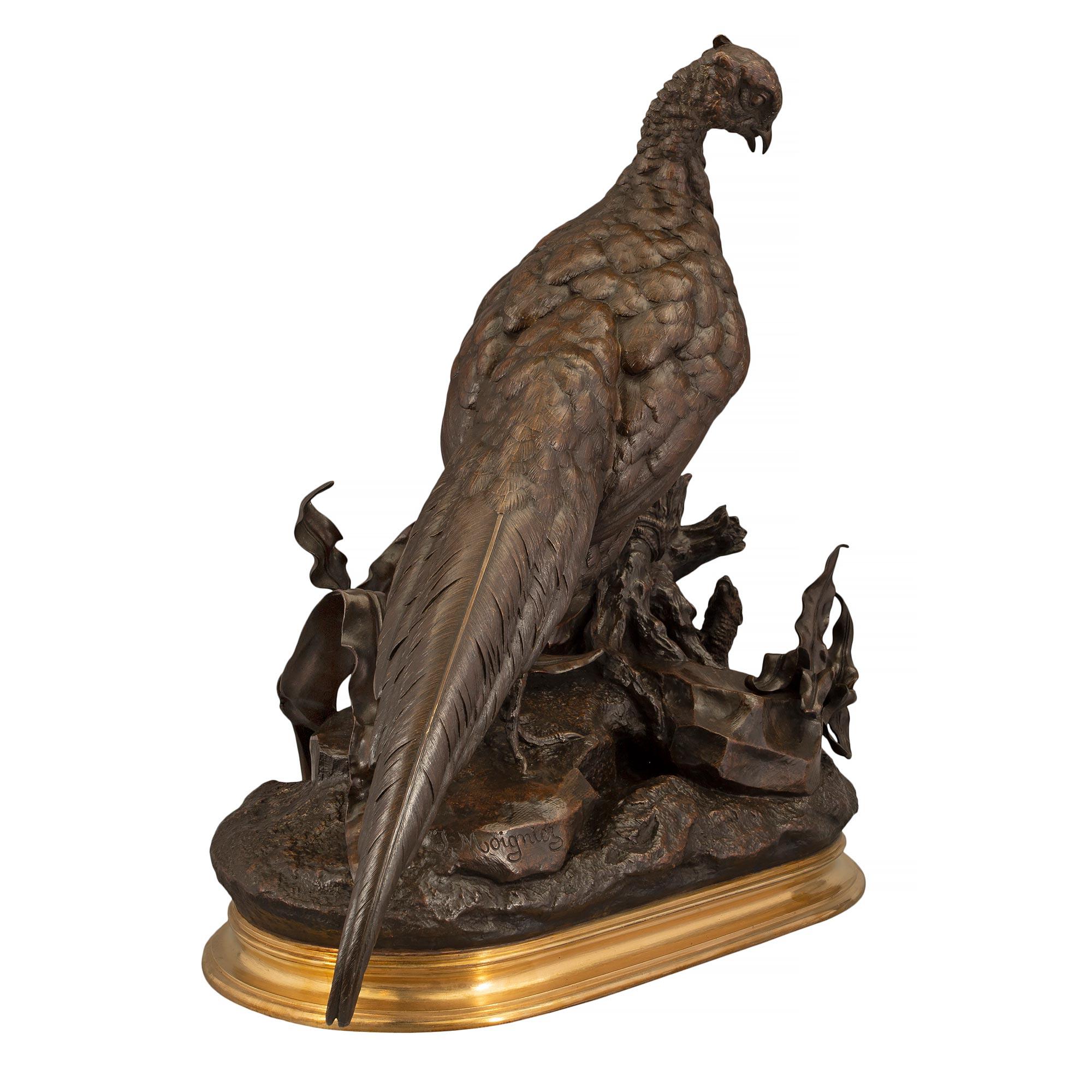 A stunning and large scale French 19th century patinated bronze and ormolu statue of a pheasant signed Jules Moigniez. The bronze is elevated above a mottled oval shaped ormolu base. The regal pheasant is stands proudly with one leg on a rock and
