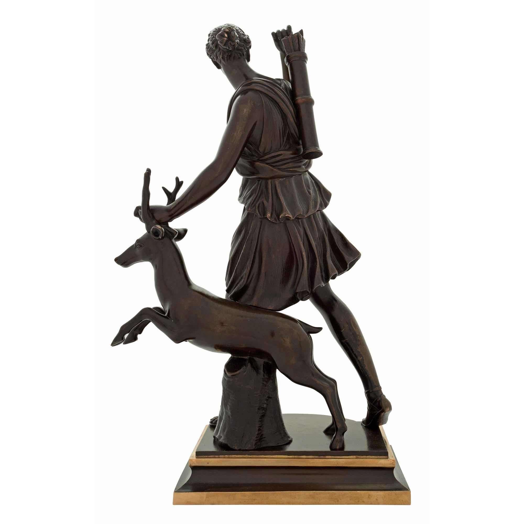 Très belle statue française du XIXe siècle en bronze patiné et bronze doré représentant Diane la chasseresse, signée Susse Frères. La statue est surélevée par une base rectangulaire mouchetée à la façade concave et aux bandes décoratives en bronze