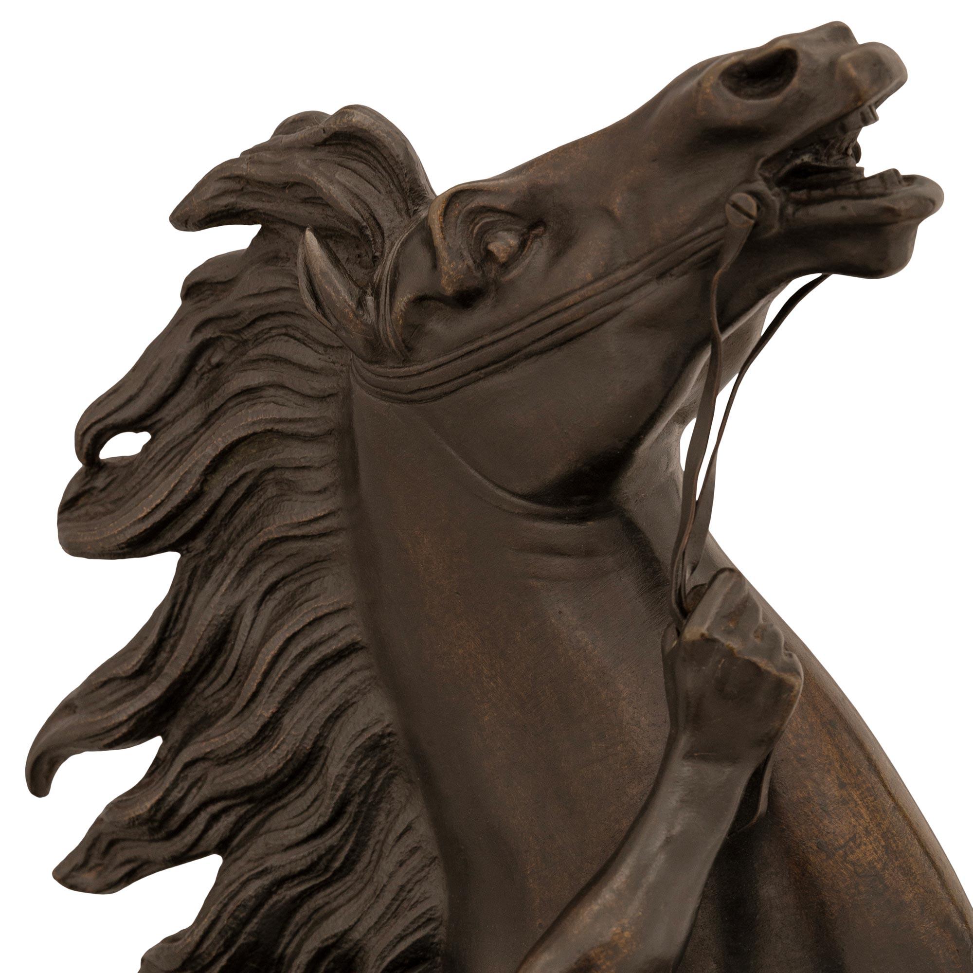 A handsome French 19th century patinated Bronze statue of a horse and groom, modeled after the horses of Marly. The excited horse is rearing up with its front legs off the ground, its mane blowing in the wind, and an animal skin draped over its