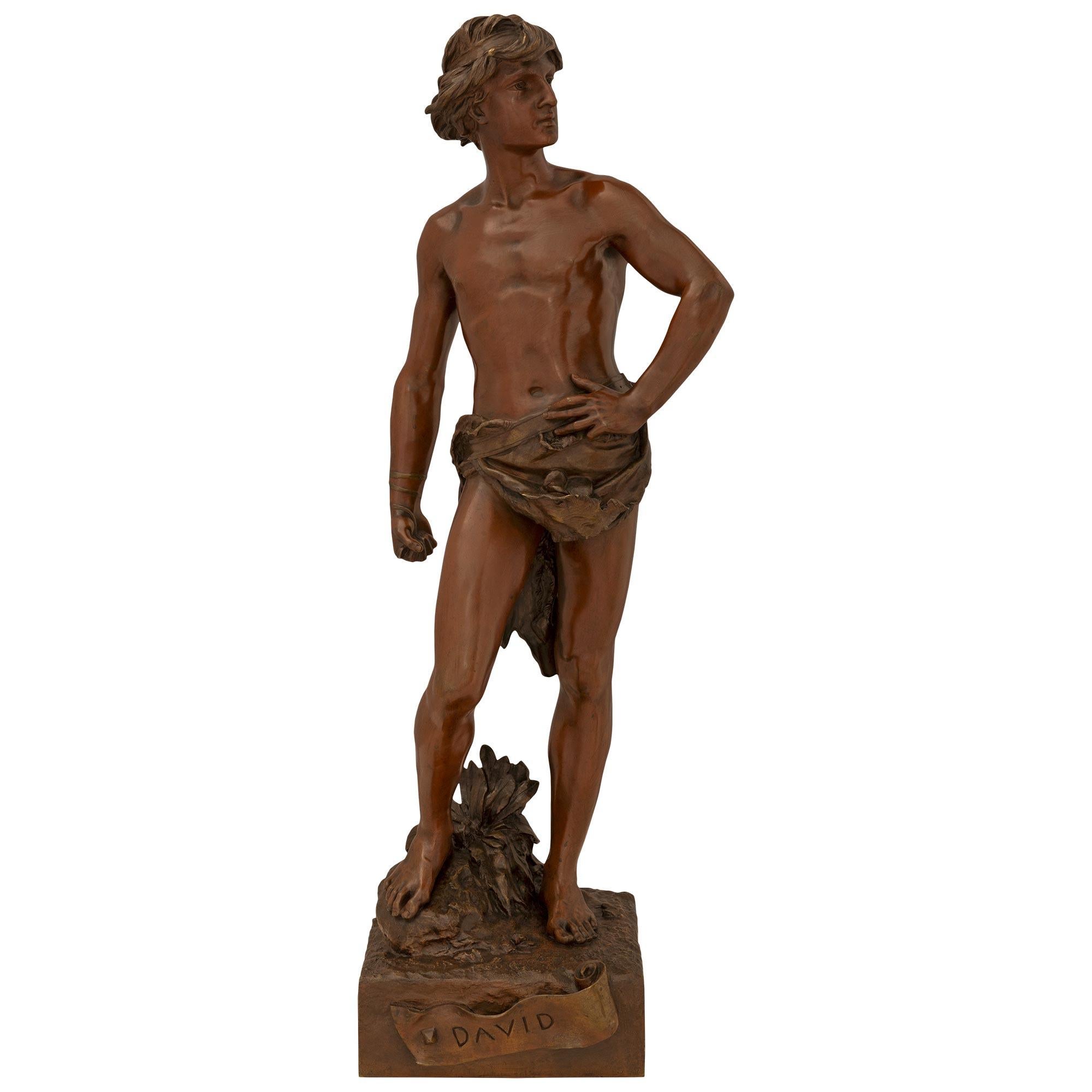 A handsome French 19th century Patinated bronze statue of a young David signed A Gaudez. The statue is raised on a square base displaying a front scroll with the name 