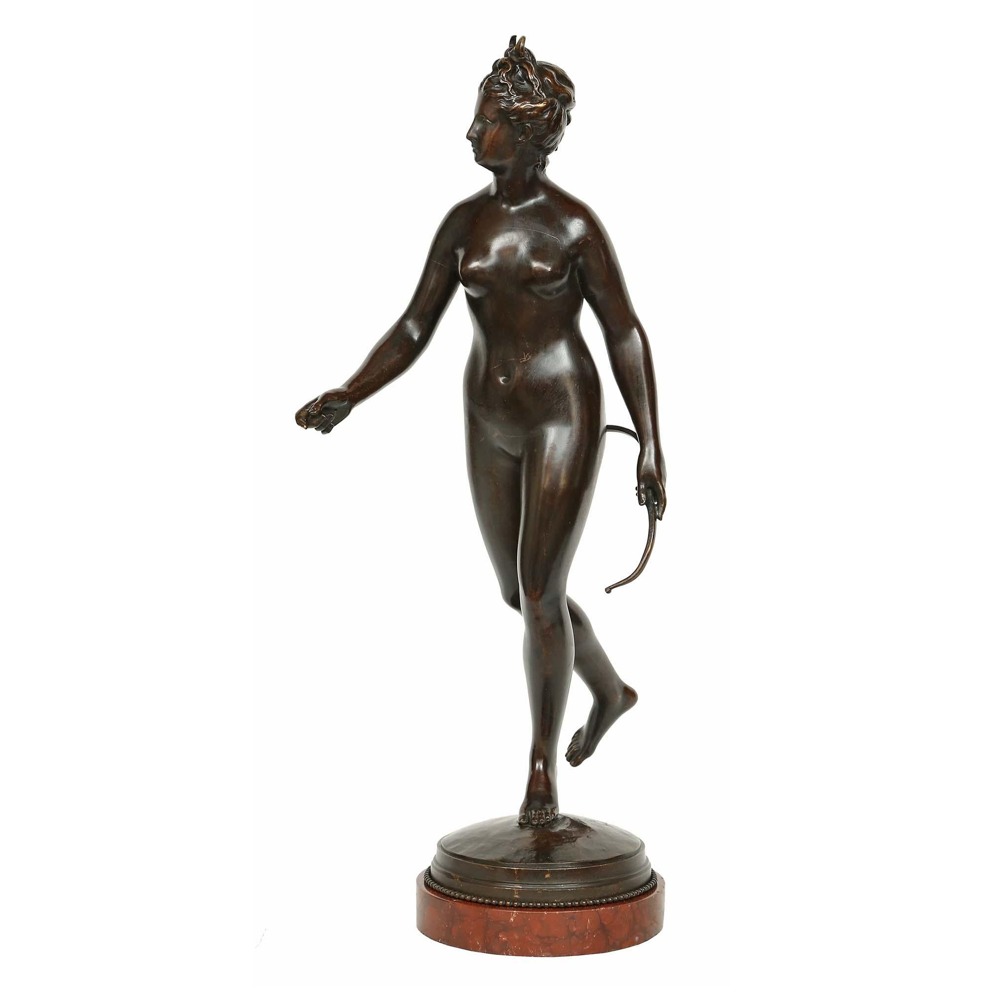 Magnifique statue française en bronze patiné du XIXe siècle représentant Diane chasseresse, signée HOUDON. La statue est surélevée par un socle circulaire en bronze Rouge Griotte et moulé. La Diane nue est extrêmement bien exécutée et semble marcher