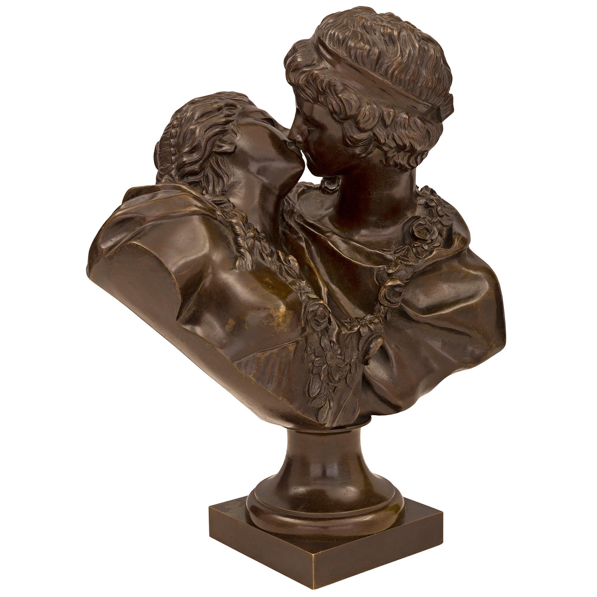 A charming and extremely high quality French 19th century patinated bronze statue of Le Baiser Donné, signed by Houdon. The statue is raised by a square base below the socle shaped pedestal. Above, the superb and most romantic patinated bronze bust