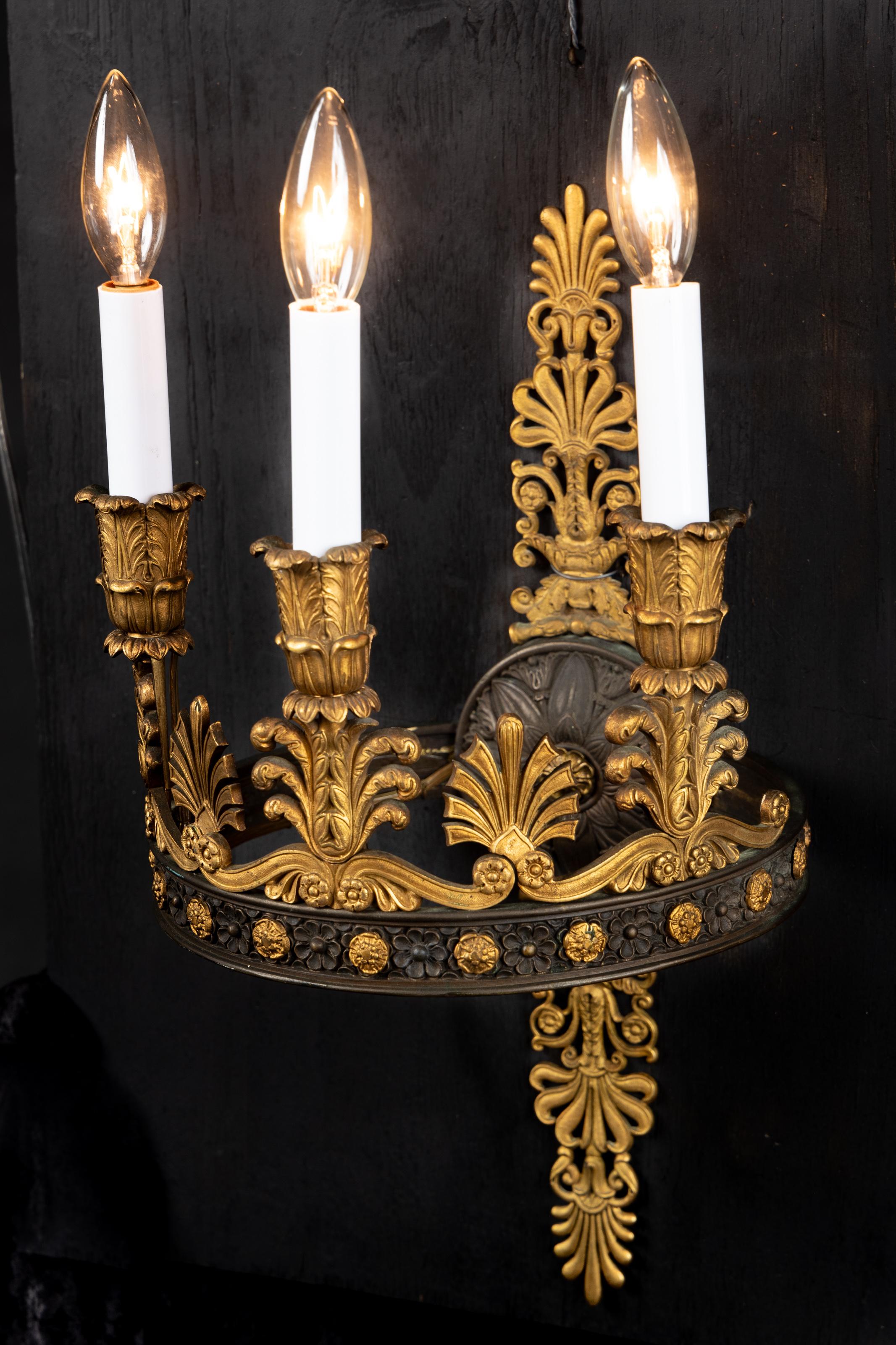 Magnificent pair of French 19th century Period First Empire round patinated bronze and bronze three light sconces with bronze candle cups of acanthus leaves, adorned with feathers, bronze fleurettes on patinated bronze ring, and elaborate