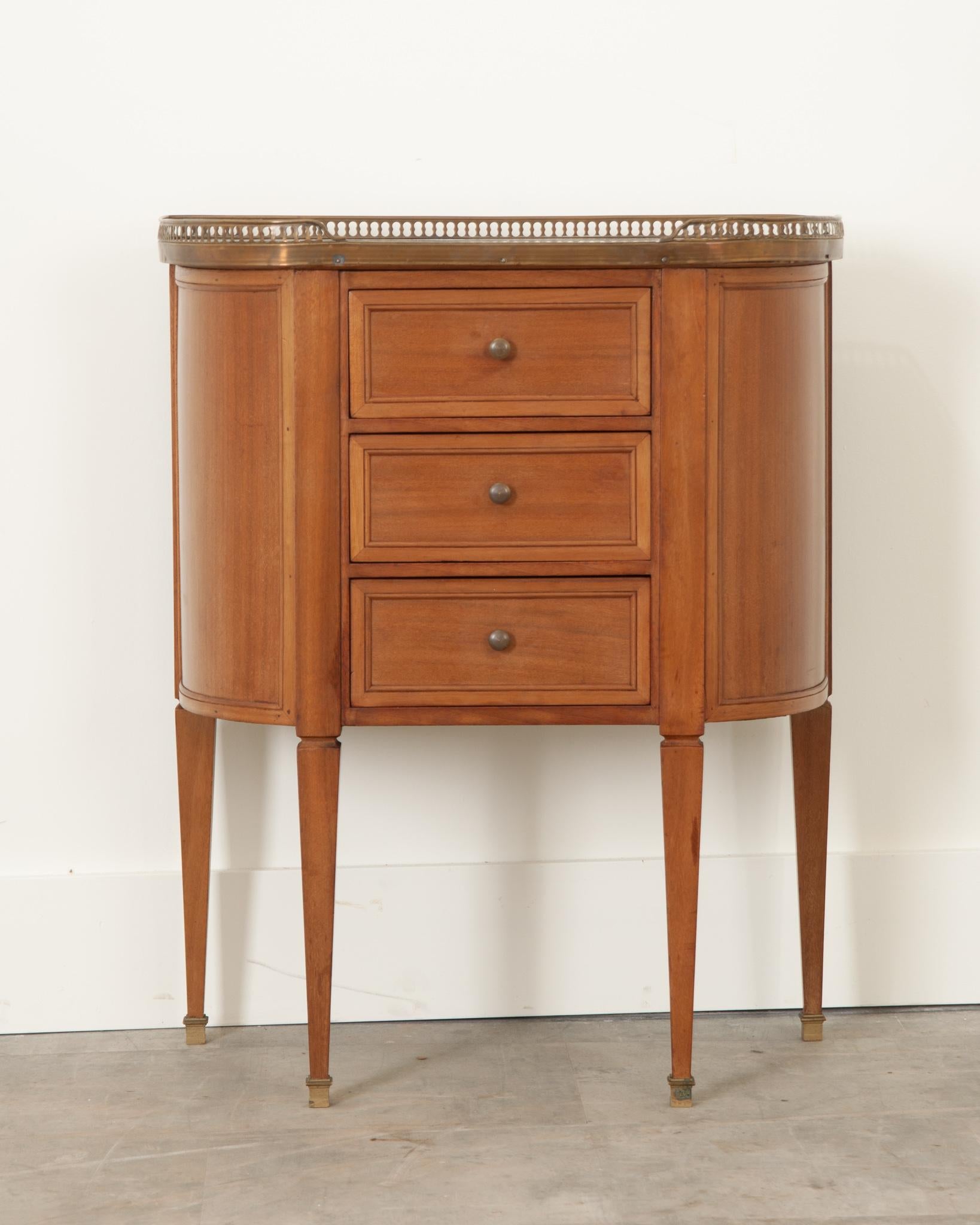 This petite mahogany bedside table was crafted in France during the 19th century. A breakfront pierced brass gallery surrounds the antique white marble top. The marble is in excellent condition. Three drawers with thumbnail molding are fixed with
