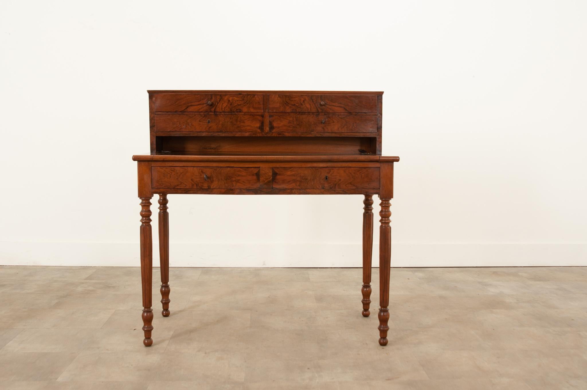 A petite antique mahogany correspondence desk that was hand-crafted in France circa 1850. Elegant and in excellent condition this desk delights with its linear shape and hand-carved details. A sleek upper console is arranged with four drawers above