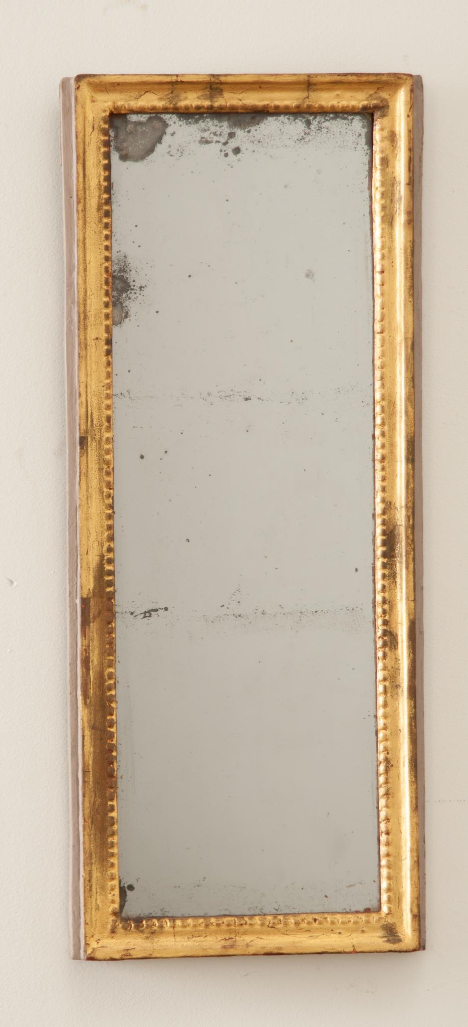 A lovely petite 19th century French mirror in a well patinated gold gilt frame. Handcrafted in France in the 1800s the worn gold gilt and underlying gesso coming through on the hand-carved frame create a truly wonderful patina and textured look. The