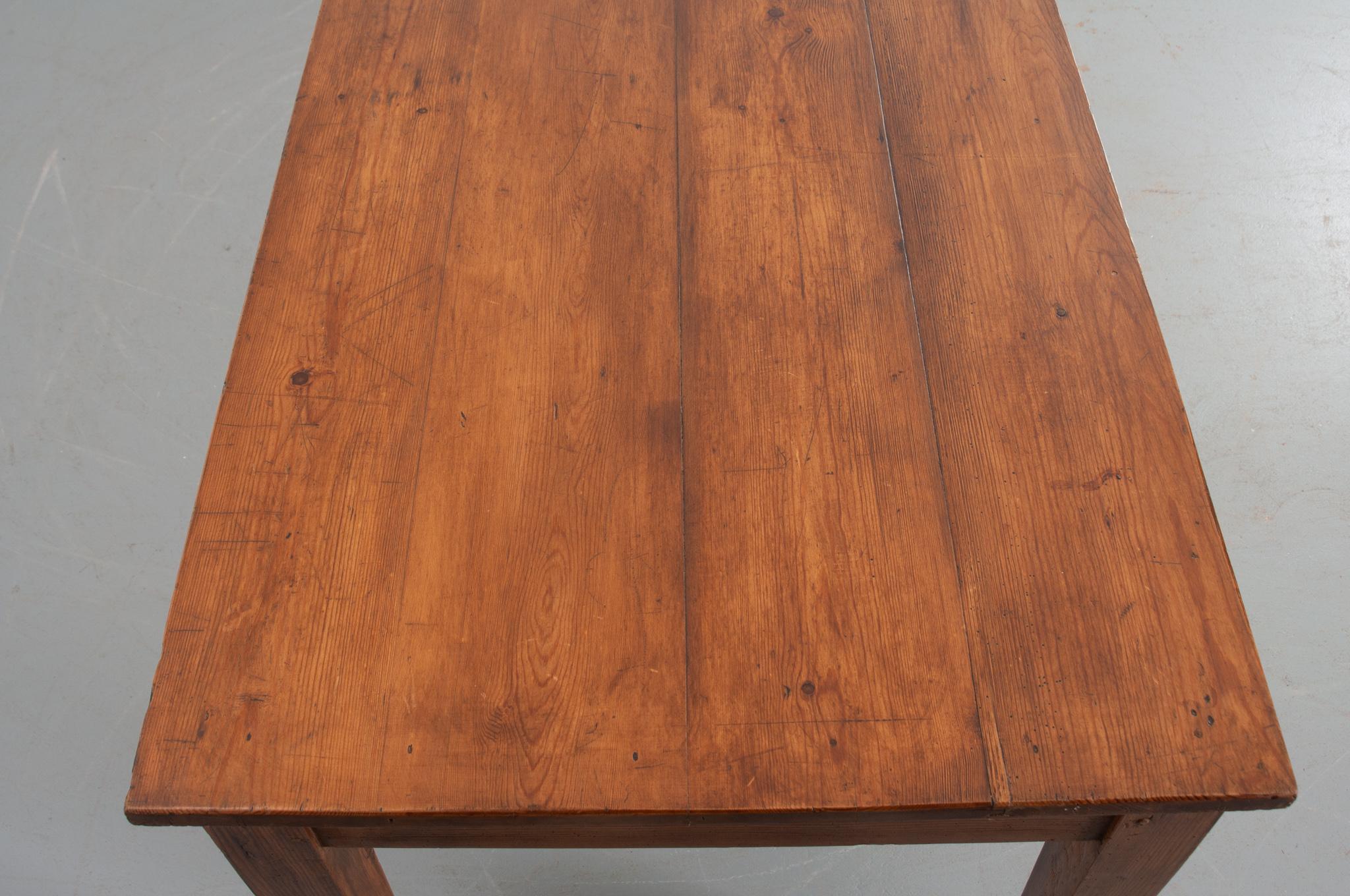 This beautiful French farm table is perfect as a dining room table because of its great length, fitting between ten to twelve chairs. Four pine planks compose the surface, full of character with a great patina, and sits atop a one drawered apron.