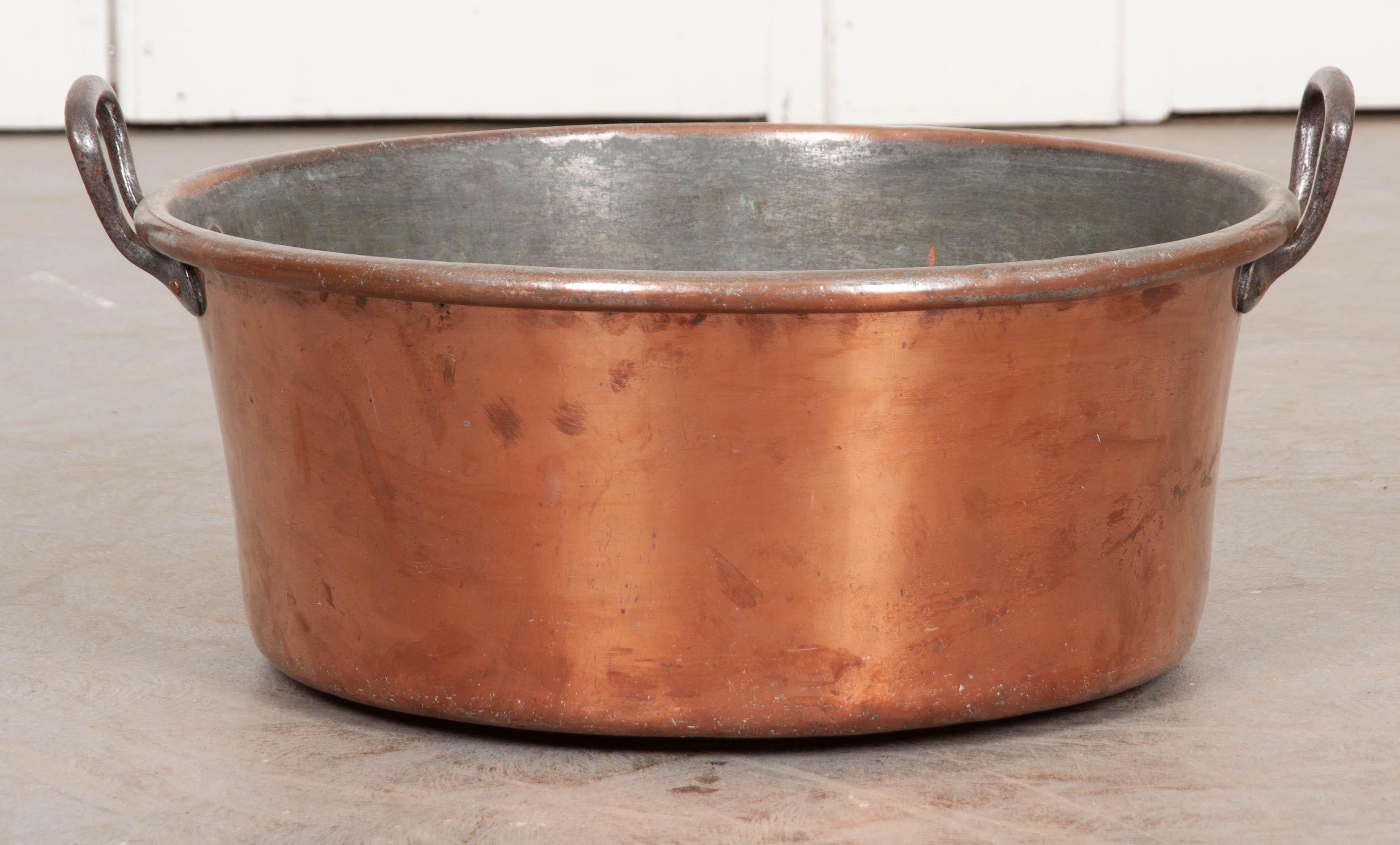 This sizable 19th century copper pot is known as a jam pan. Used in the production of fine jams and jellies, these large vessels often have large iron handles and would be used to cook down the fruit and sugar. Today, this piece would be an