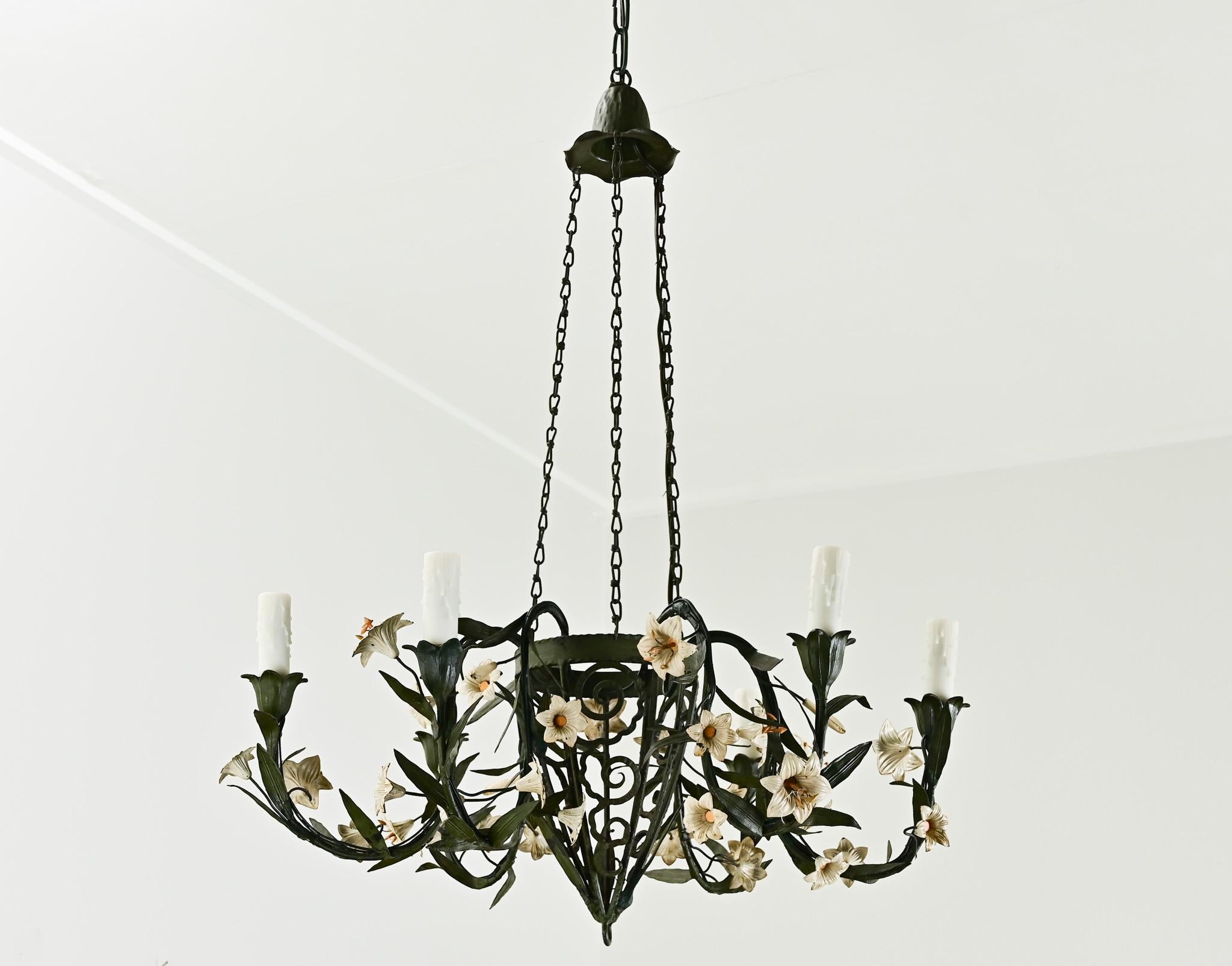 A whimsical French 6-light chandelier from the 1800’s has an iron frame with painted ceramic flowers hanging from six curved chandelier arms with faux wax candle covers. Cleaned and wired for US electrical using UL listed parts and is ready to hang