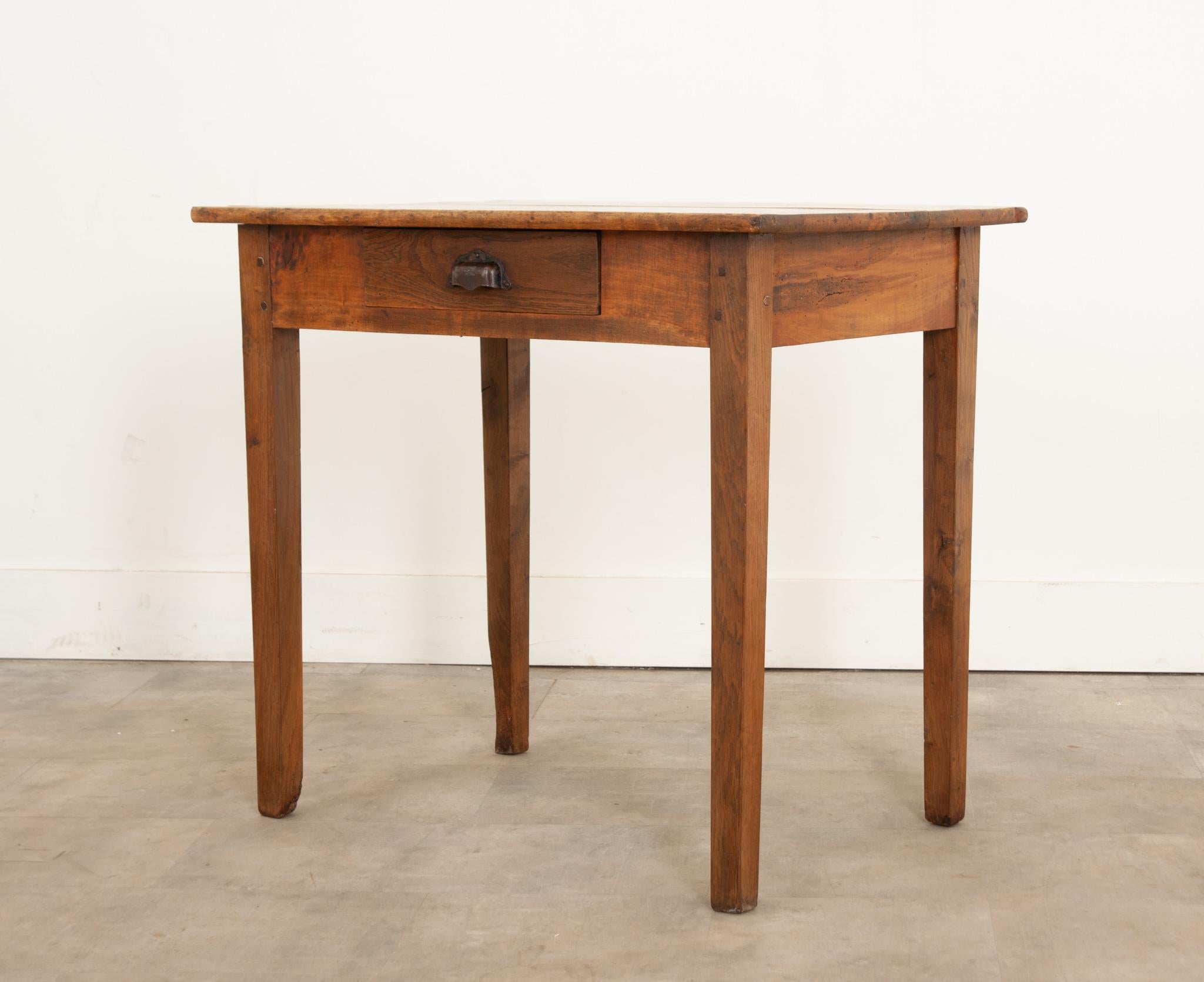 Crafted in France during the 1880s, this rustic little table is made of solid poplar. Its wonderfully patinated hardwood apron has a single drawer effaced with its original, shaped metal bin pull. The apron connects to square, slightly tapered legs.