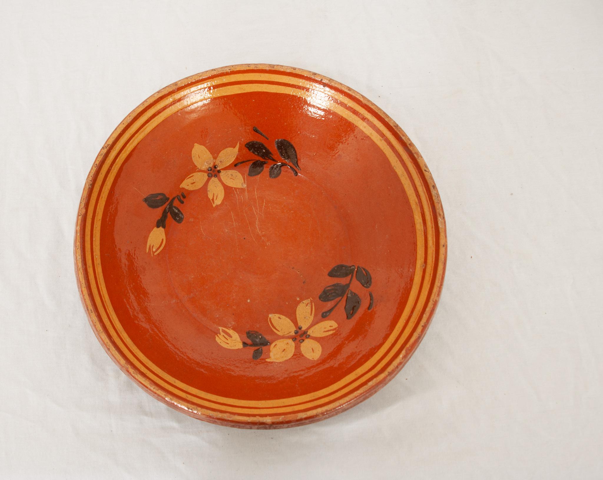 A fetching French 19th century pottery bowl of vibrant color with floral designs. This bowl has been glazed a lively warm orange with a maize yellow trim on the rim and incorporated into the delicate flowers painted in the interior. This is a lovely