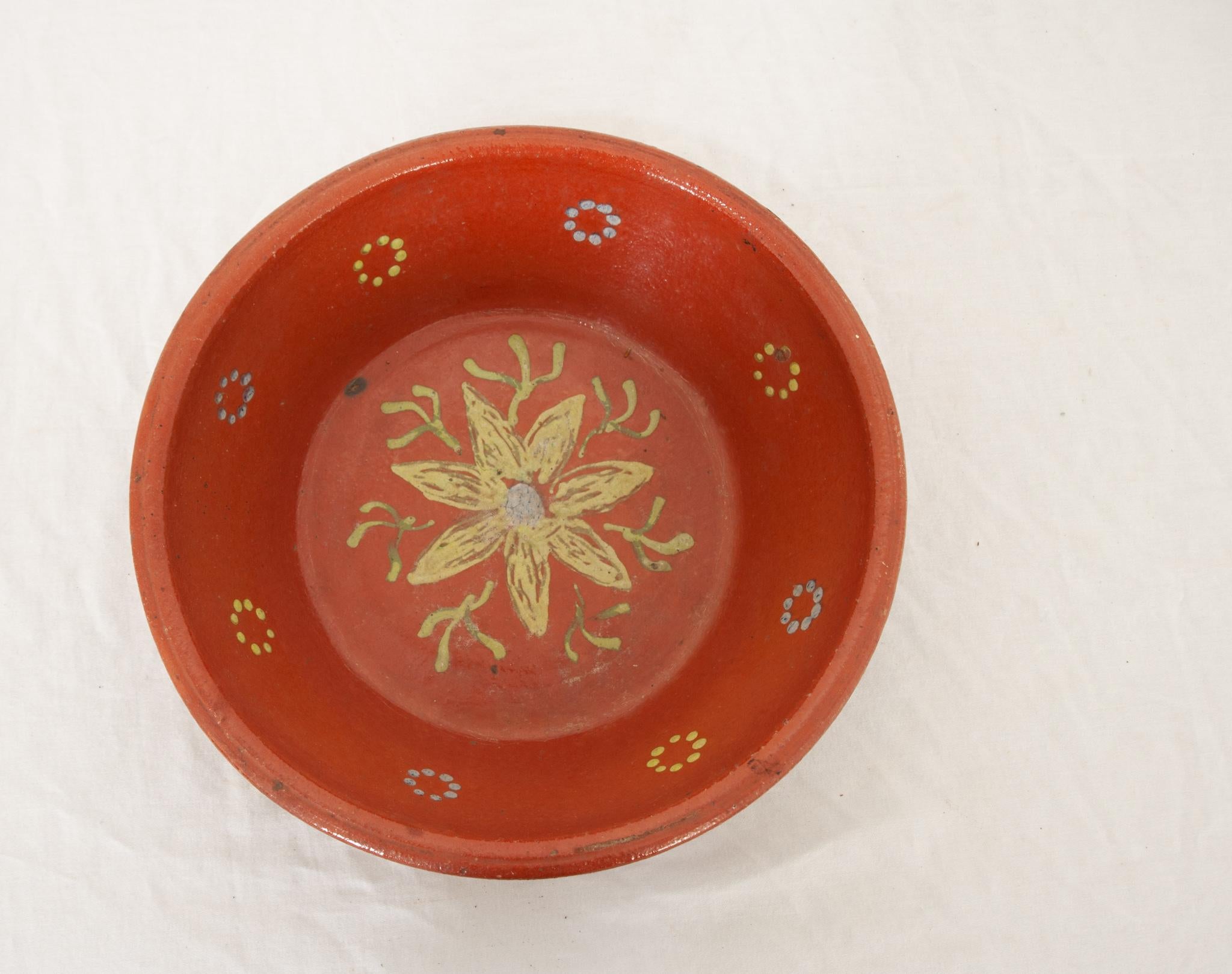A delightful French 19th century pottery bowl of vibrant color with floral designs. This tall bowl has been glazed a lively warm orange with maize yellow and pale blue rosettes and delicate flower and vine painted in the interior. This is a lovely
