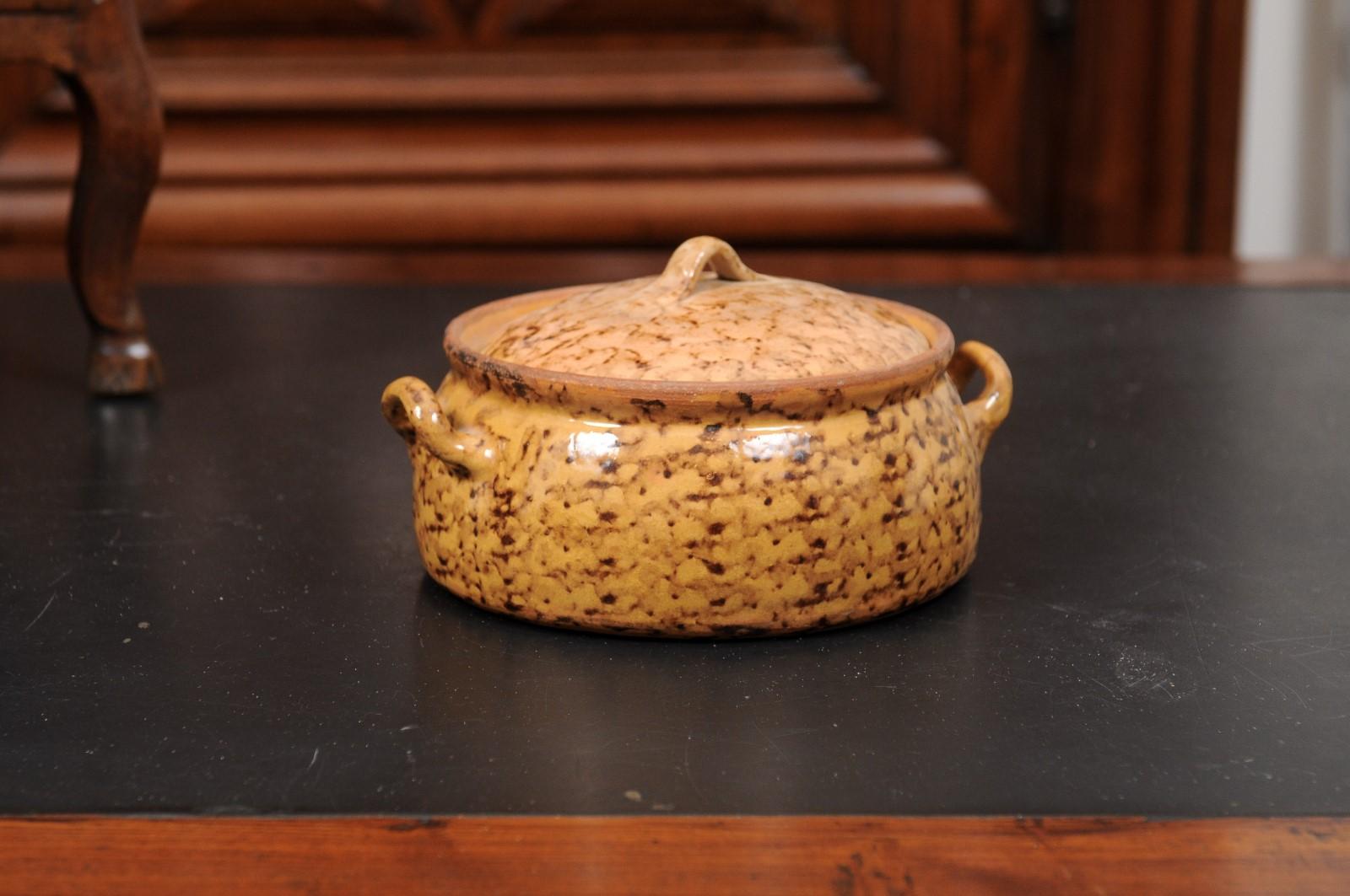 A French pottery covered baking dish from the 19th century, with brown glaze and lateral handles. Created in France during the 19th century, this pottery baking dish features a circular body topped with a small lid and adorned with a mustard glaze