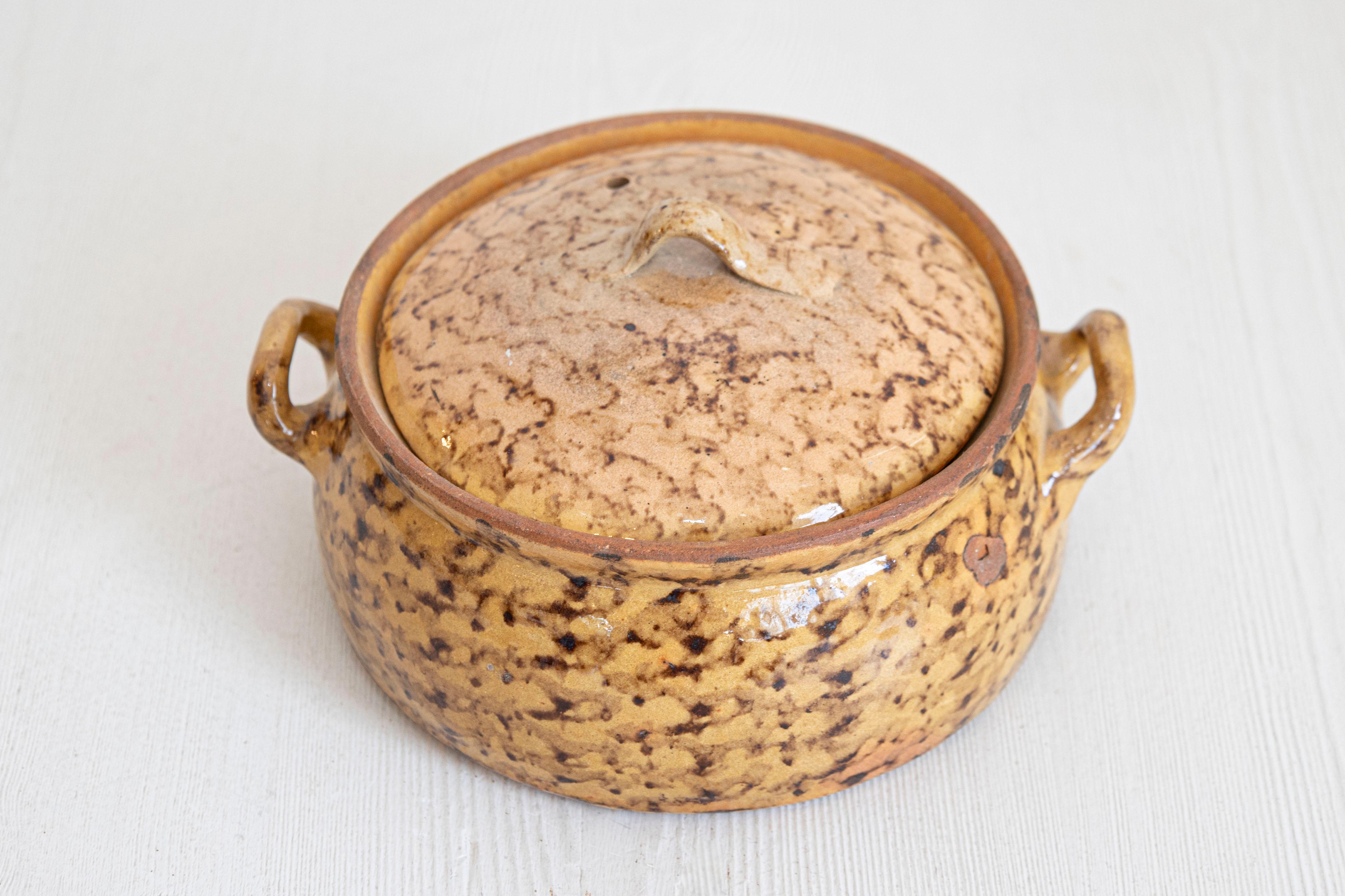 Un plat à four couvert en poterie française du 19e siècle, avec glaçure brune et poignées latérales. Créé en France au cours du XIXe siècle, ce plat à four en poterie présente un corps circulaire surmonté d'un petit couvercle et orné d'une glaçure