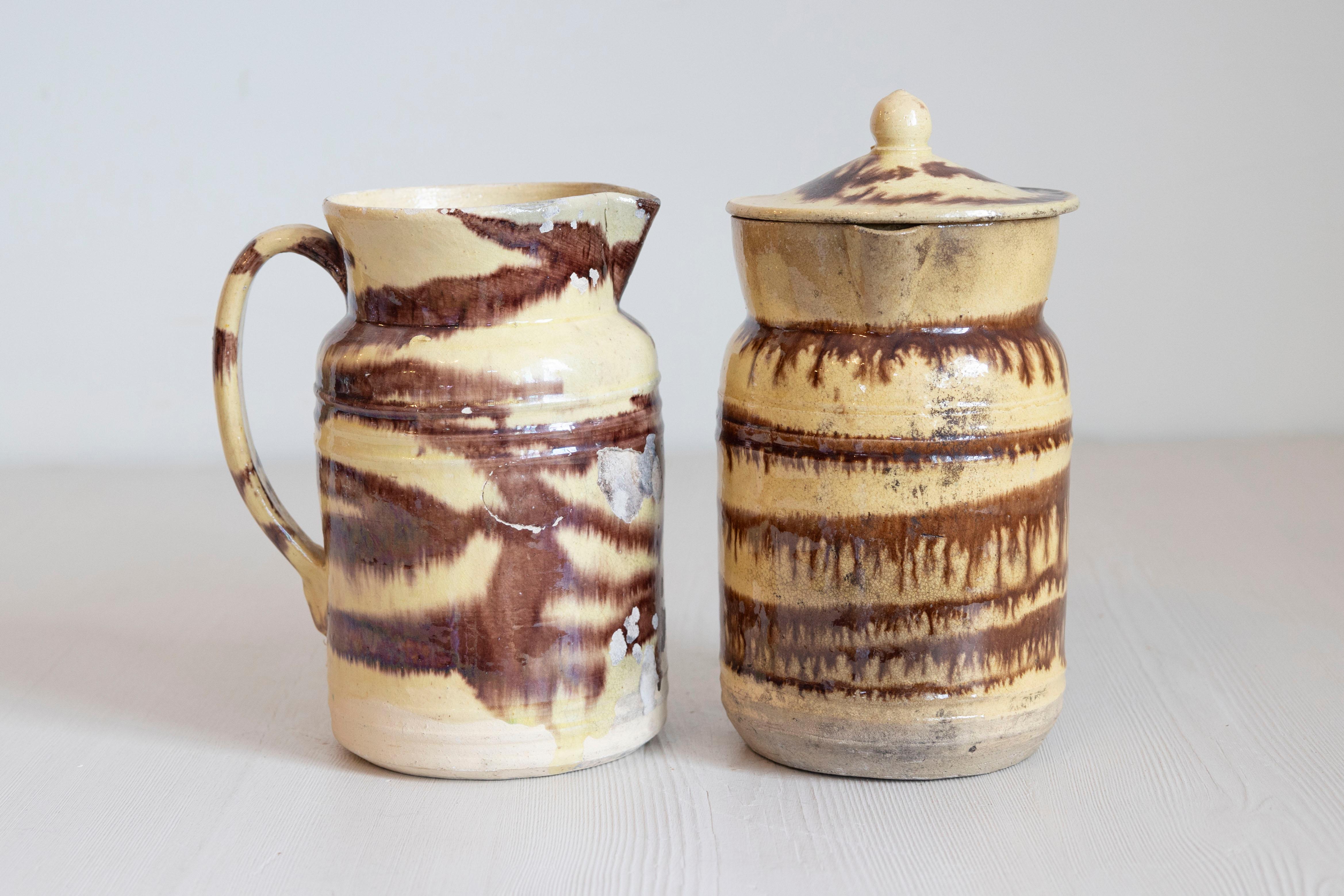 Deux pichets en poterie française du 19e siècle à glaçure crème et brune, vendus 395 $ chacun. Créées en France au cours du XIXe siècle, ces pichets présentent un fond crème joliment contrasté par une glaçure brune appliquée avec des effets de