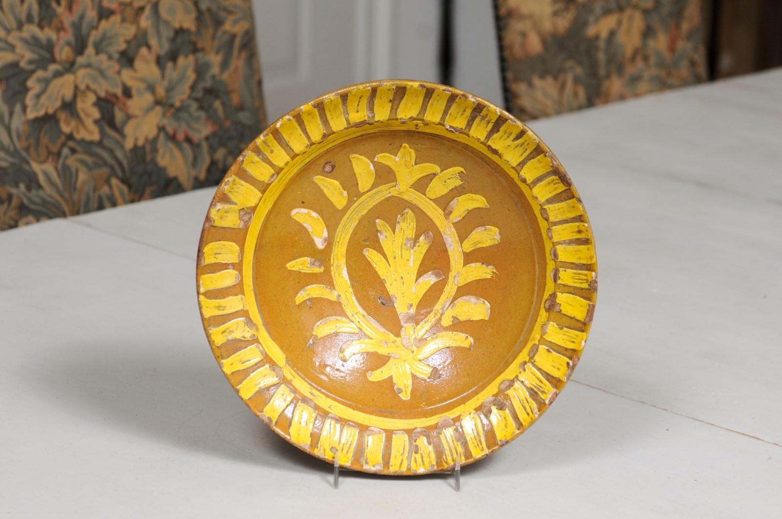 A French pottery soup plate from the 19th century, with yellow starburst motifs and stylized foliage. Created in France during the 19th century, this rustic plate features a brown ground contrasted by a bright yellow glazed décor, showcasing