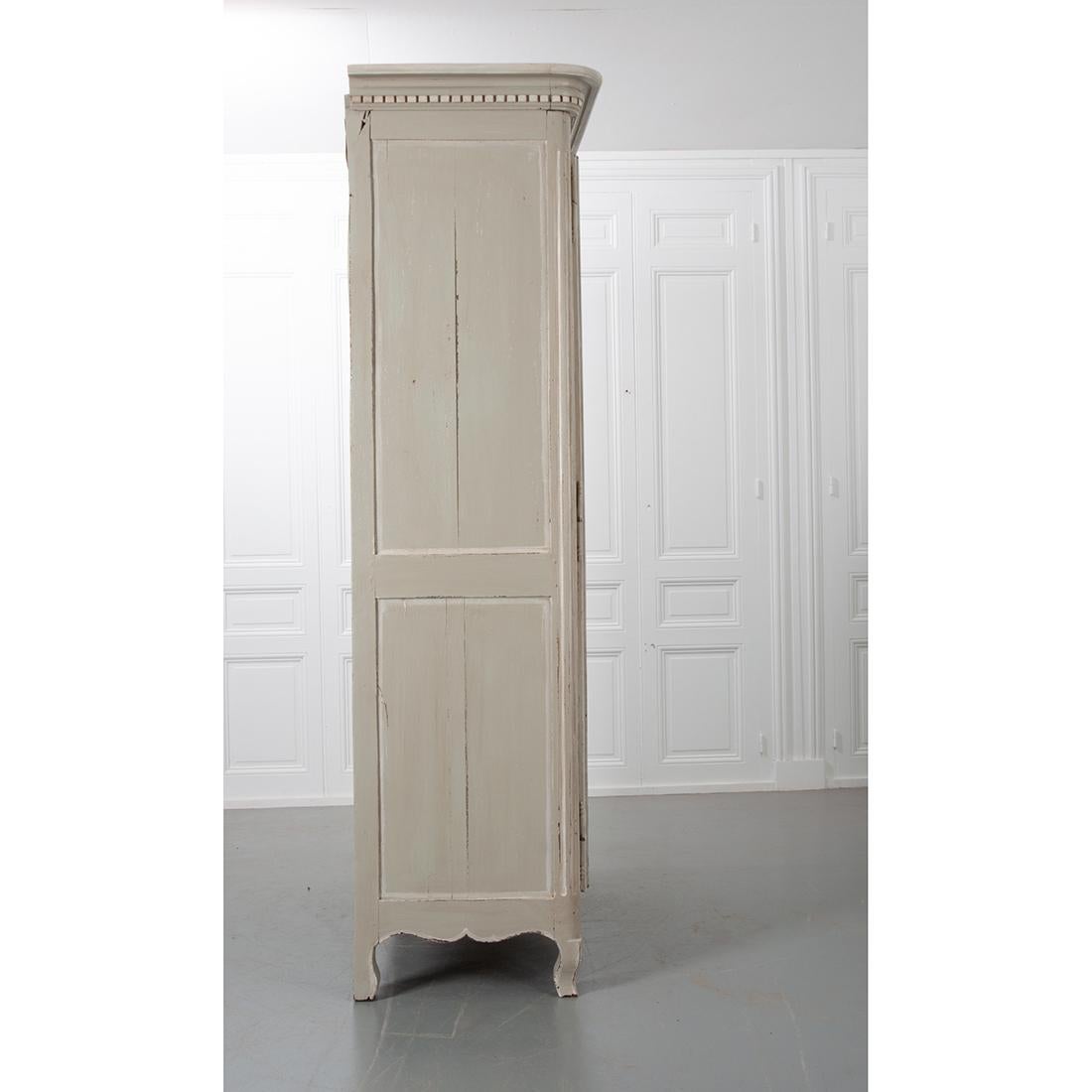A nice, hand carved and painted armoire from 19th century France. It is crowned with dentil molding and graced with two large, shapely paneled doors with beautiful carvings. Musical instruments and floral reliefs grace the center of each door. The