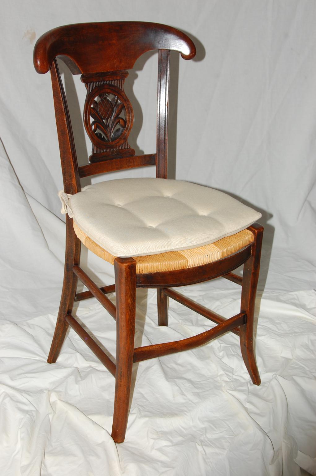French Provincial 19th century set of six dining chairs, pineapple carved curved backs, box stretchers, splay legs, rush seats with custom made tie on buttoned, reversible cream colored pads. The pattern of the rushing is of two types but is all in