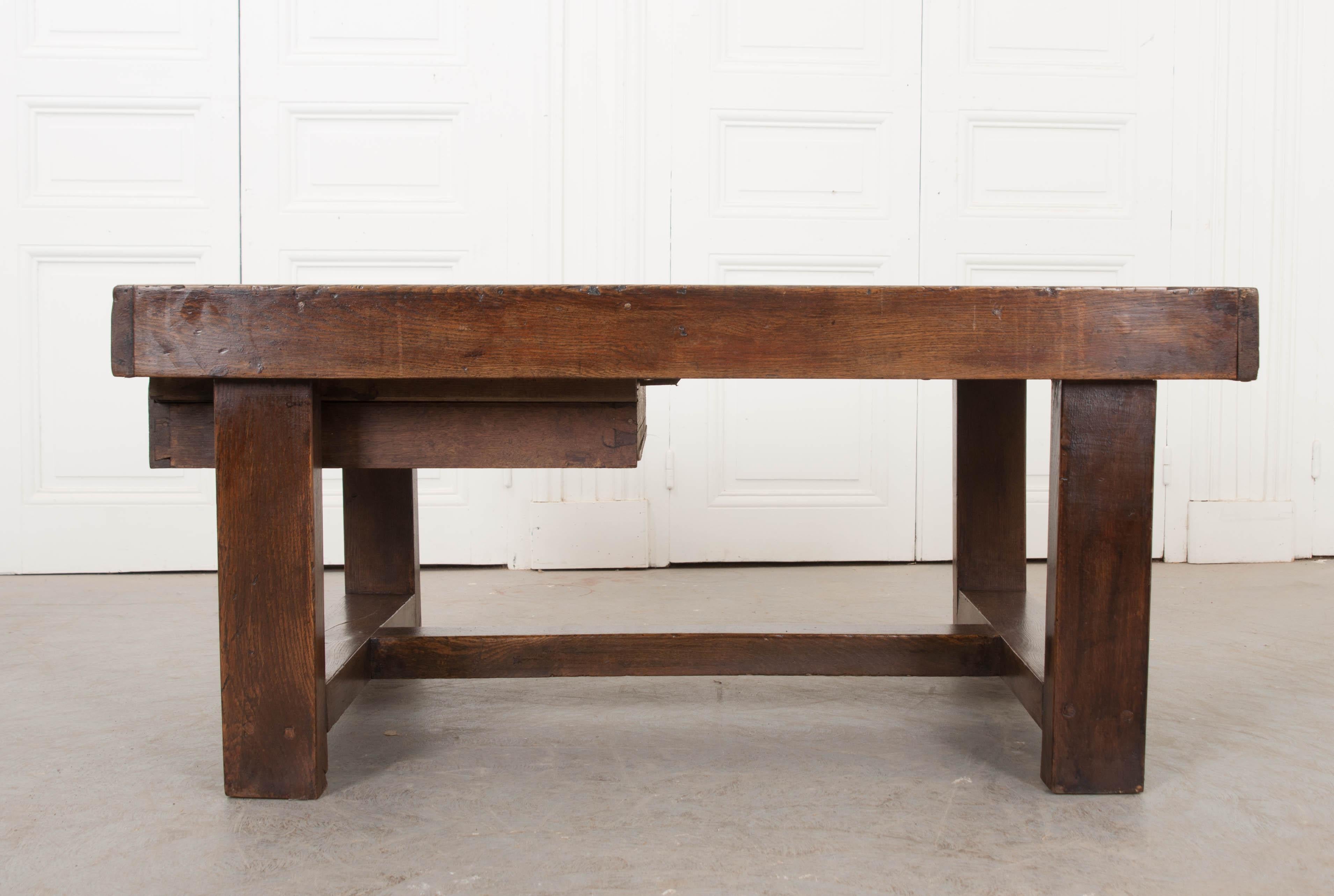 This handsome and weighty French provincial oak low table, circa 1850s, features a rich patina from years of use. Of generous proportion, it is outfitted with a single divided side-drawer and rests upon a large H-form stretcher.