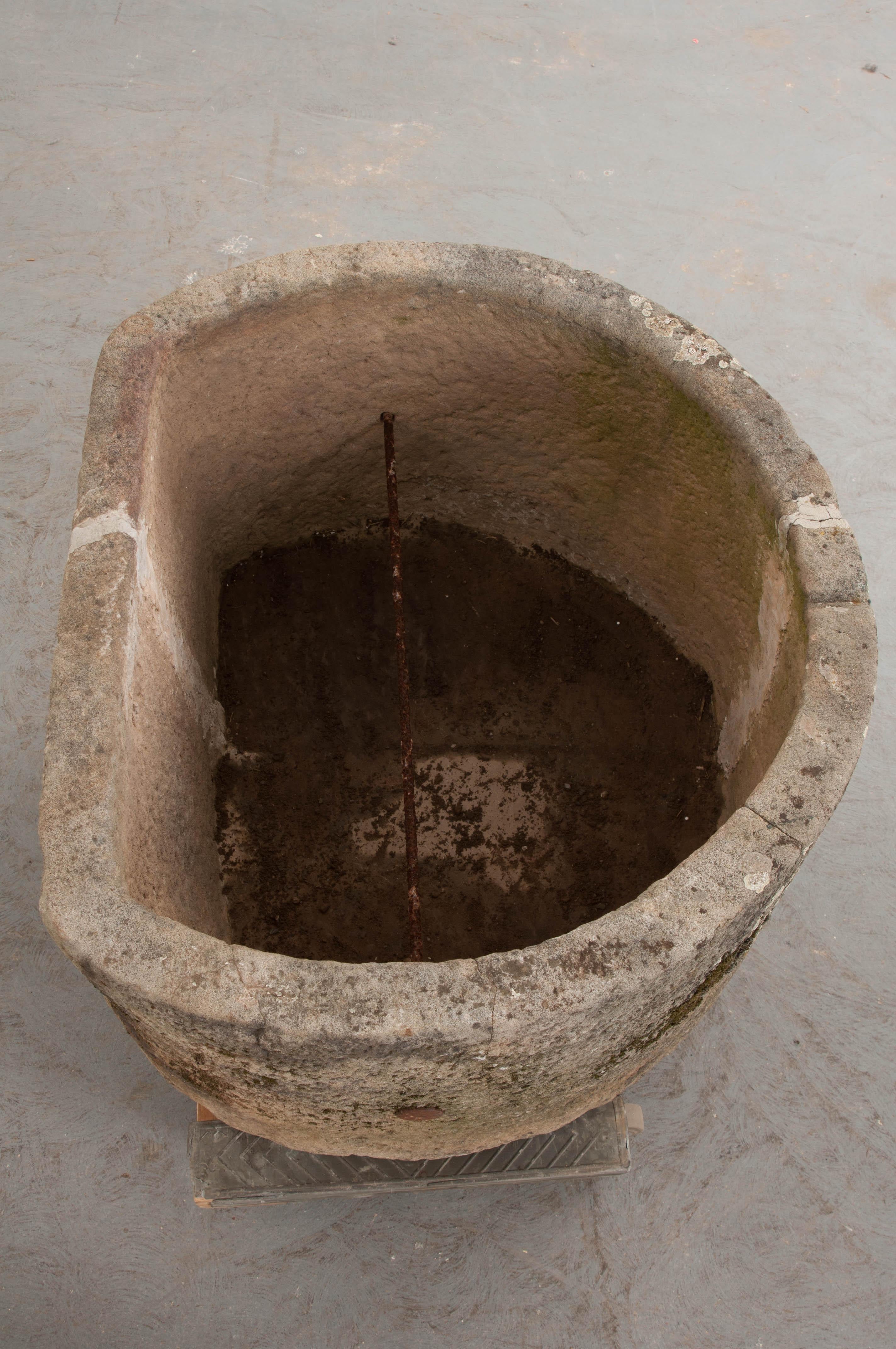 A wonderful hand-carved and chiseled stone watering trough, circa 1850s, from provincial France. Of partial circular section with a flat back for wall mounting, the interior is outfitted with an iron crossbar. There was likely a second perpendicular