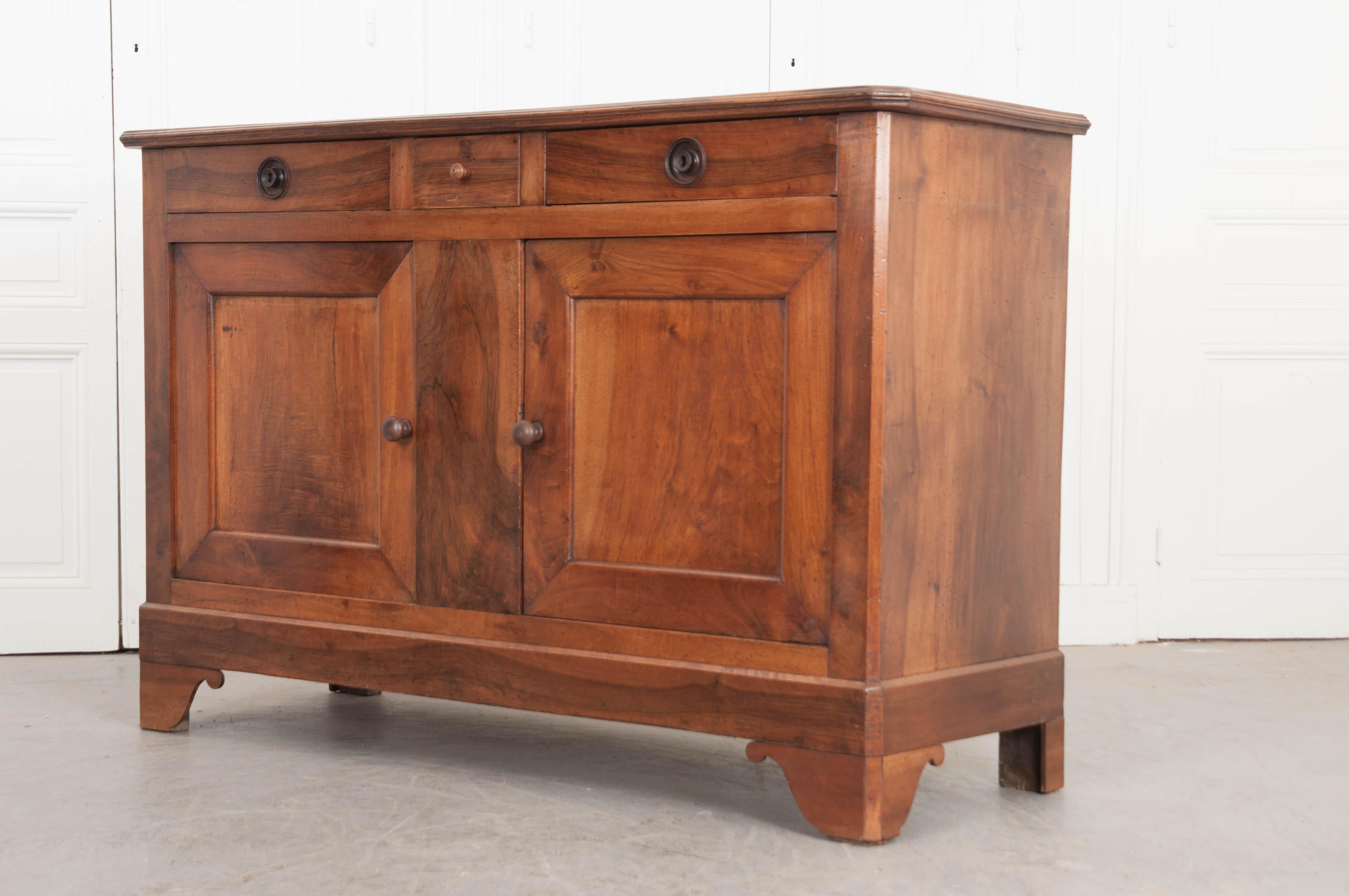 This wonderful 19th century French provincial walnut buffet, circa 1870s has a rich, warm finish that is beautifully highlighted by a professional French polish. It features a small central drawer flanked by a pair of larger ones, each having turned