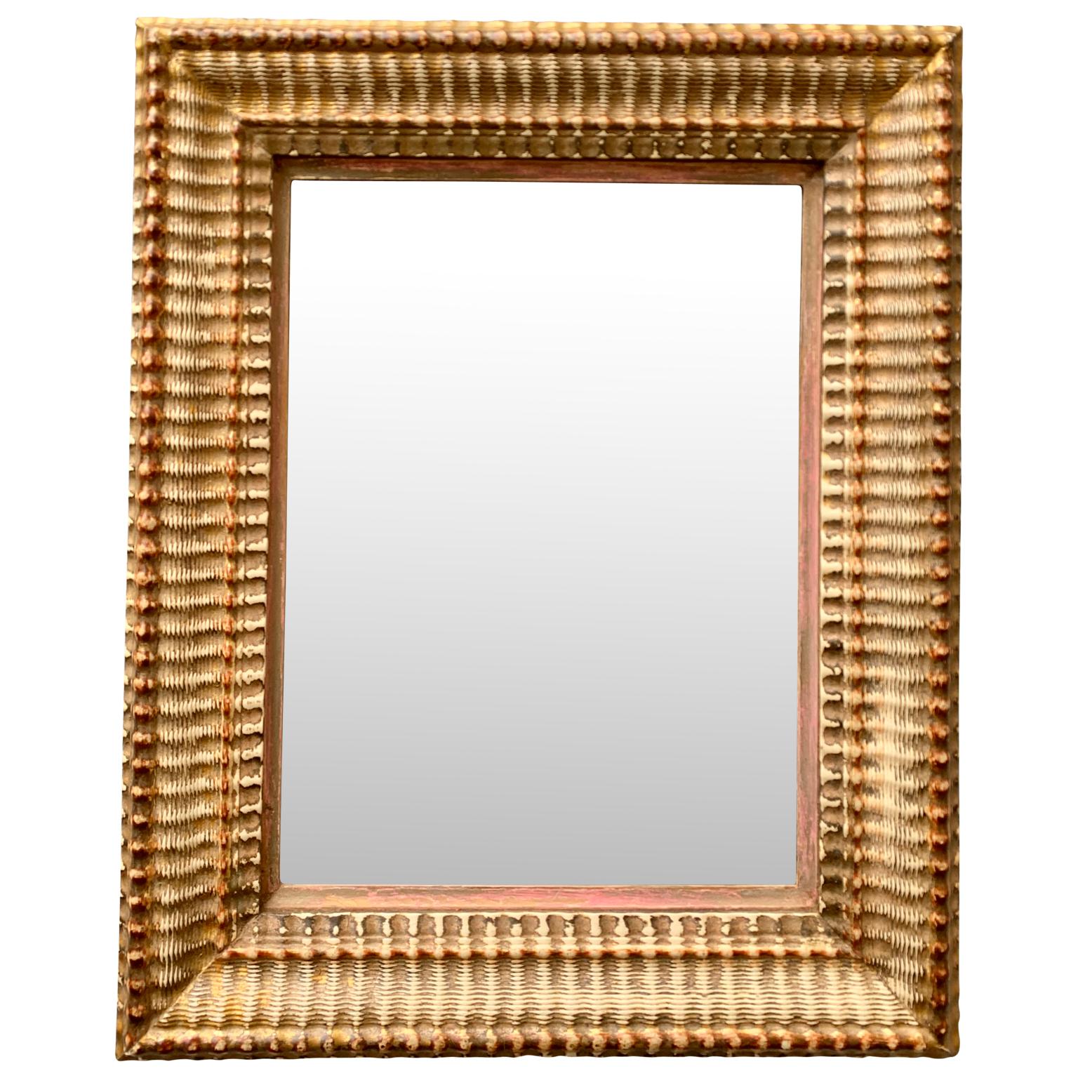 An early 19th Century French guilted mirror with wave shaped form. Original patina and wear to gold leaf surface, wear the ground color and material emerge showing the age appropriate patina.
Mirror glass is the original piece.
  