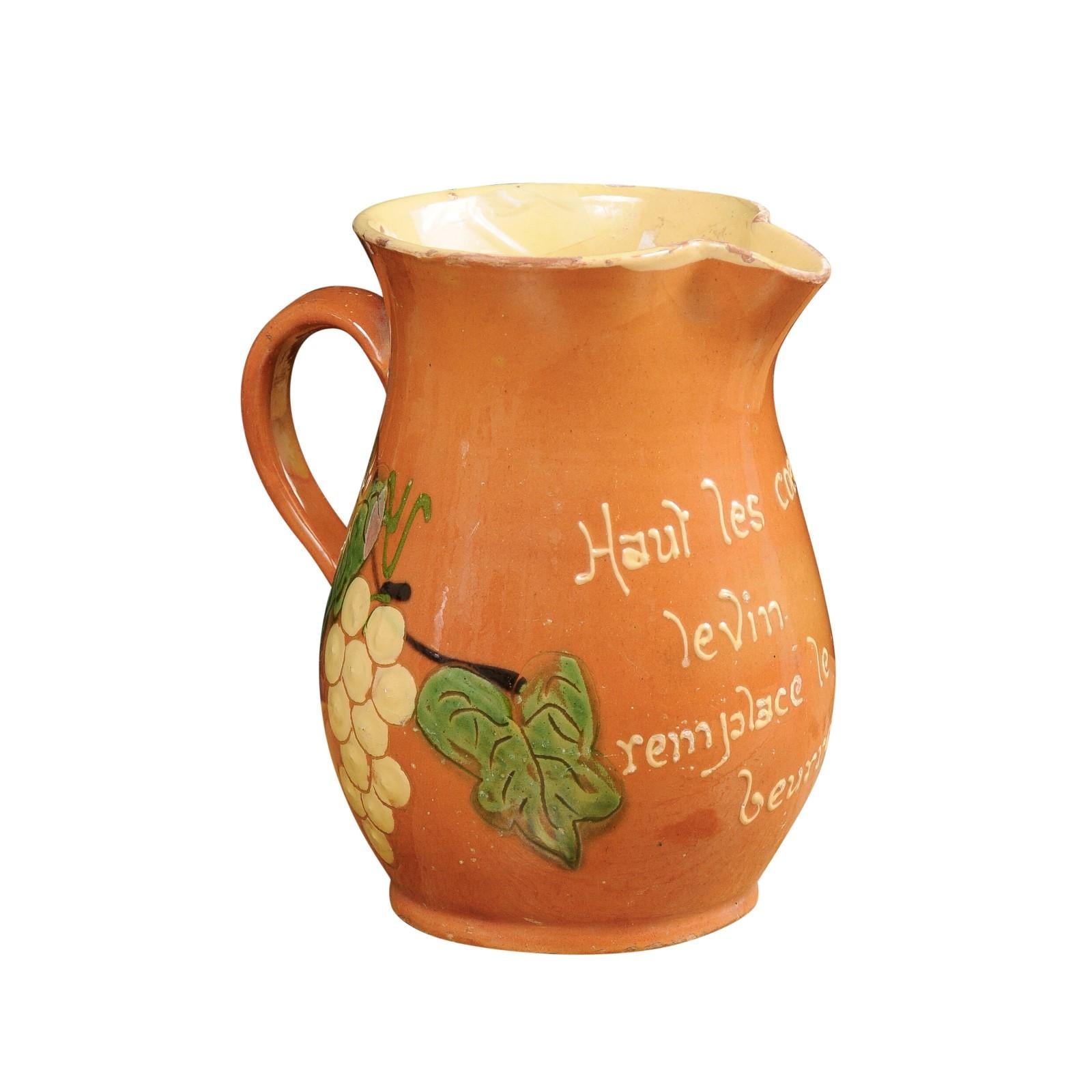 One French redware wine pitcher from the 19th century, with orange, cream, green glaze and grape motifs. Created in France during the 19th century, each of this pair of redware pitchers charms us with its vivid colors perfectly accented with grape