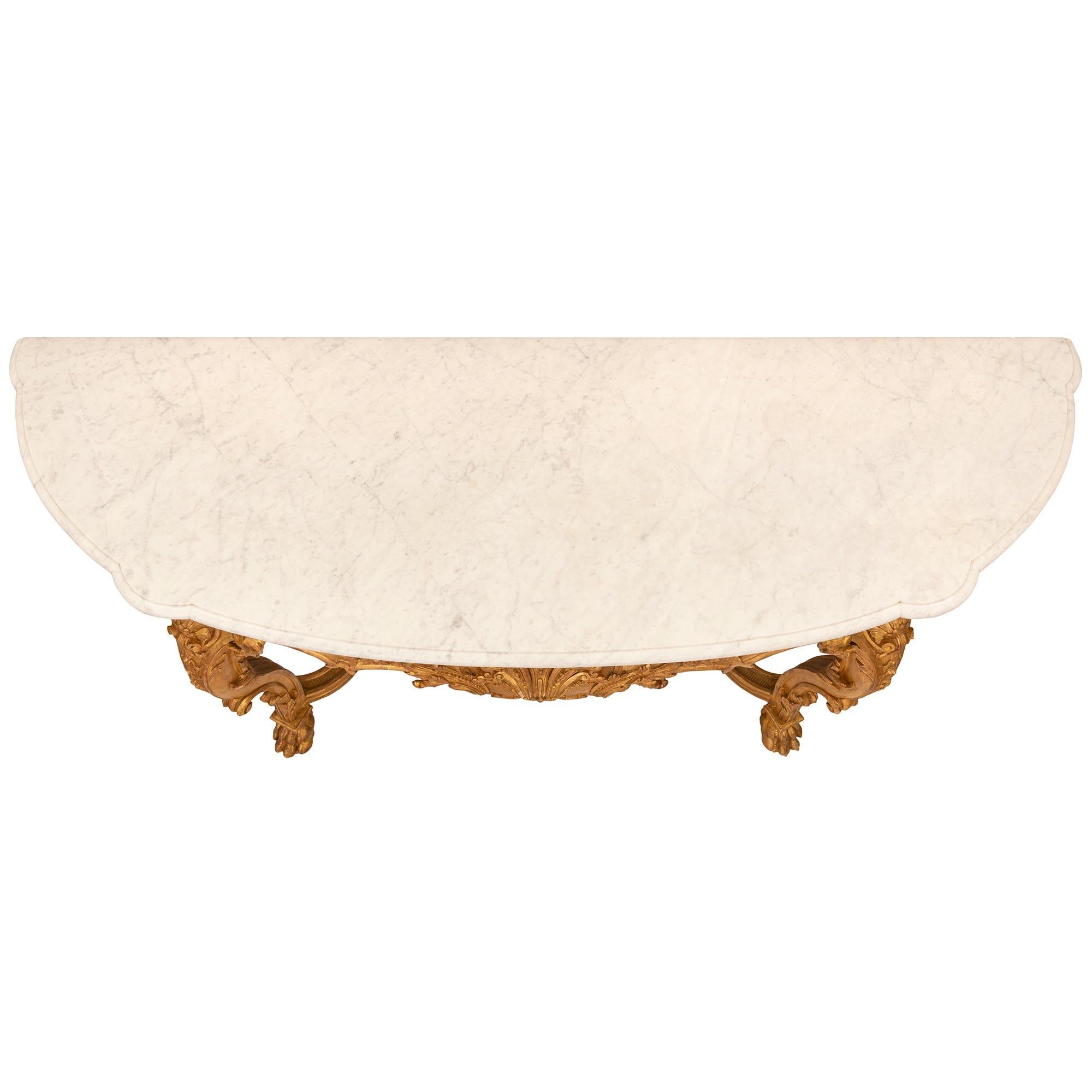 A spectacular and very high quality French 19th century Regence st. giltwood and white Carrara marble console. The freestanding console is raised by beautiful scrolled tapered legs with handsome paw feet and exceptional scrolled foliate designs,