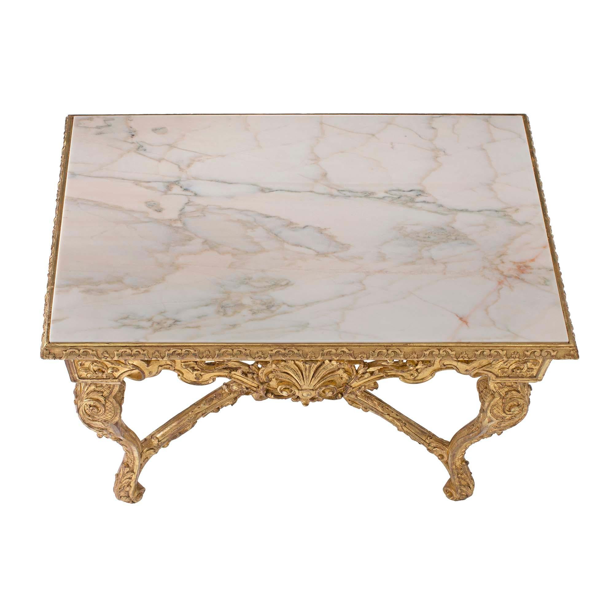 A beautiful French 19th-century Regence st. giltwood console with marble top. The console is raised on lovely cabriole legs adorned with large scrolls and opulent foliate details. The legs are joined by an X-shaped stretcher centered with a rosette