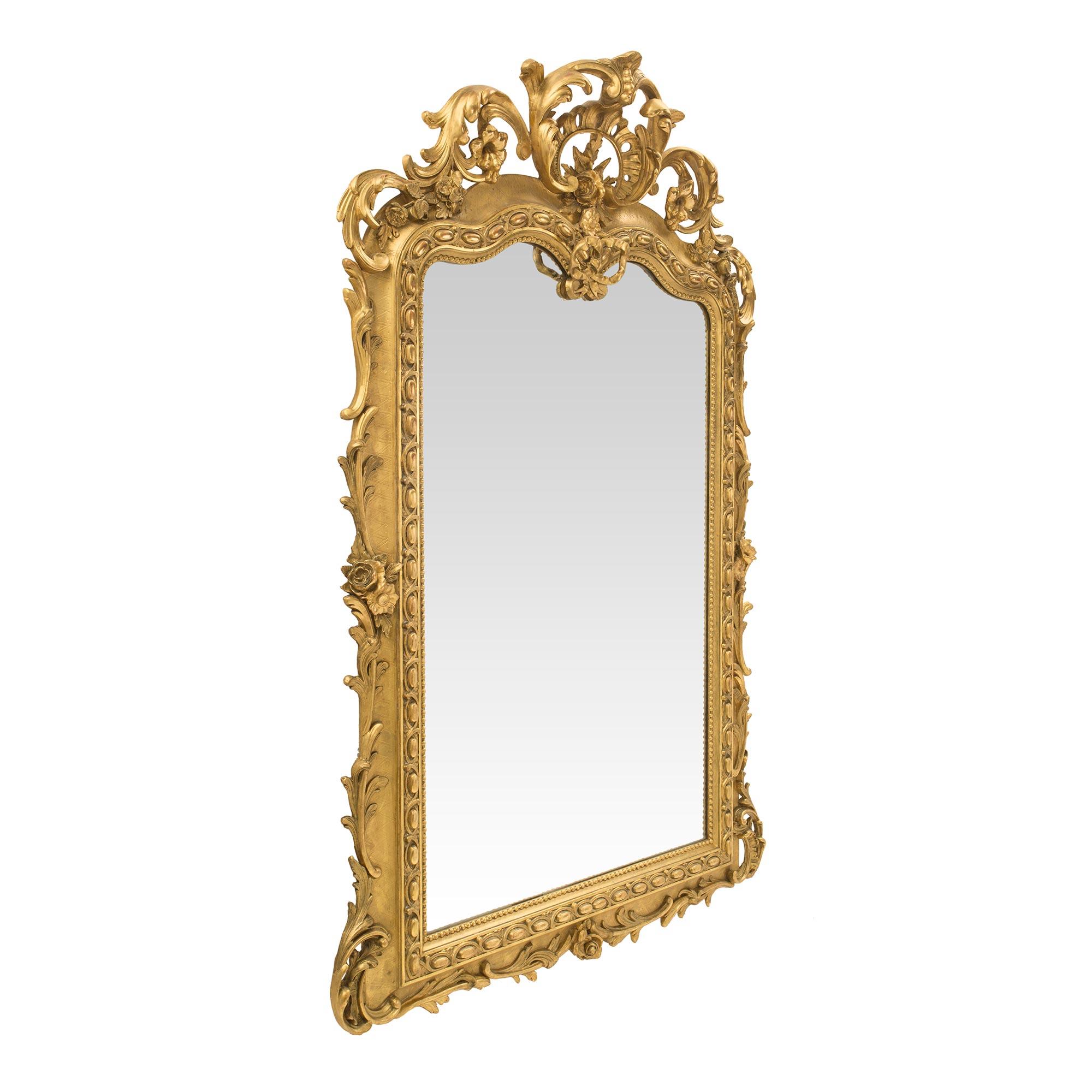 A most elegant French 19th century Regence st. giltwood mirror. The original mirror plate is framed within a beaded border and a beautiful pattern of burnished ovals within fine foliate interlocking movements. At the bottom and leading up the sides