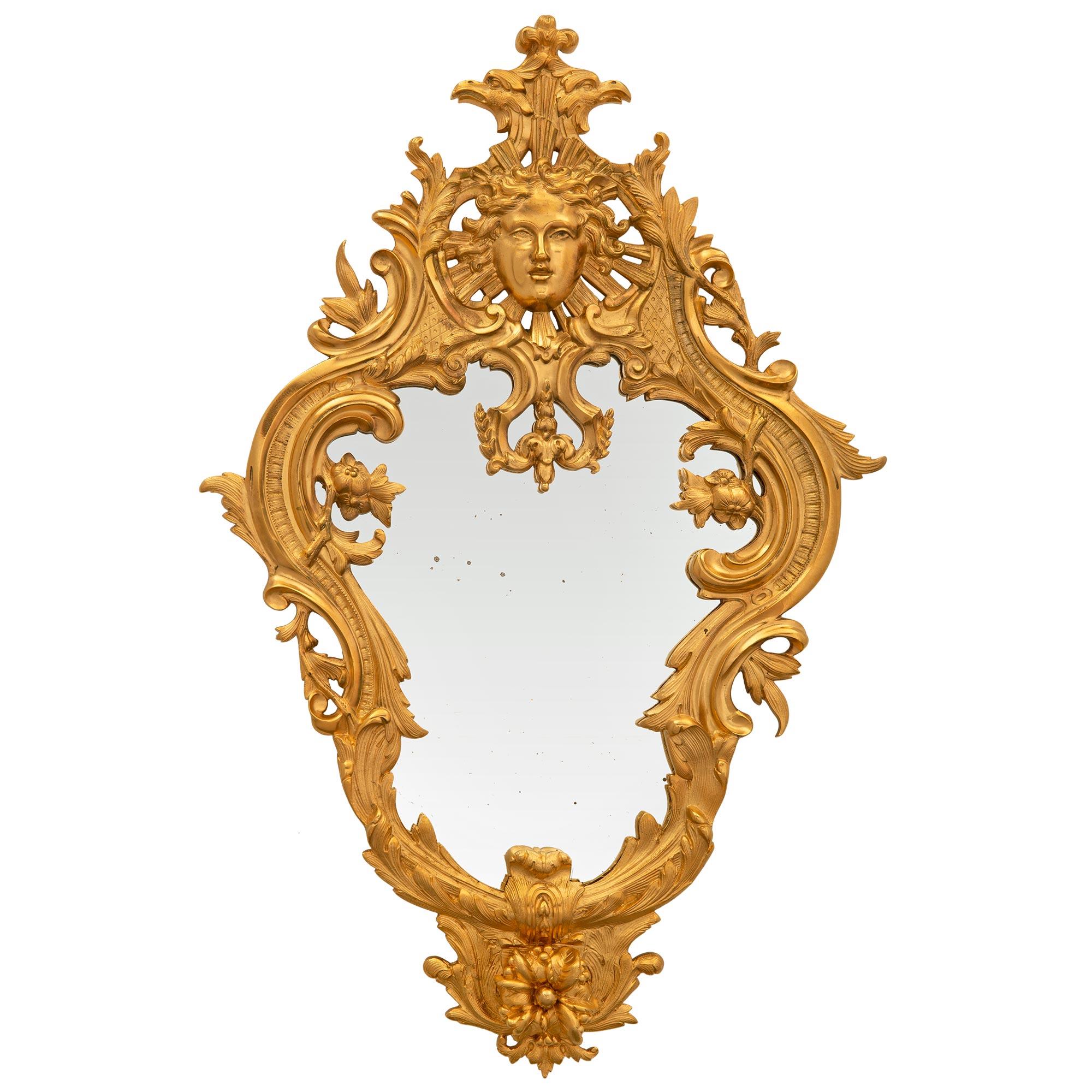 A beautiful French 19th century Régence st. giltwood mirror. The mirror retains its original mirror plate set within a charming and most elegant scalloped giltwood frame. The frame displays a richly carved floral reserve amidst acanthus leaves at