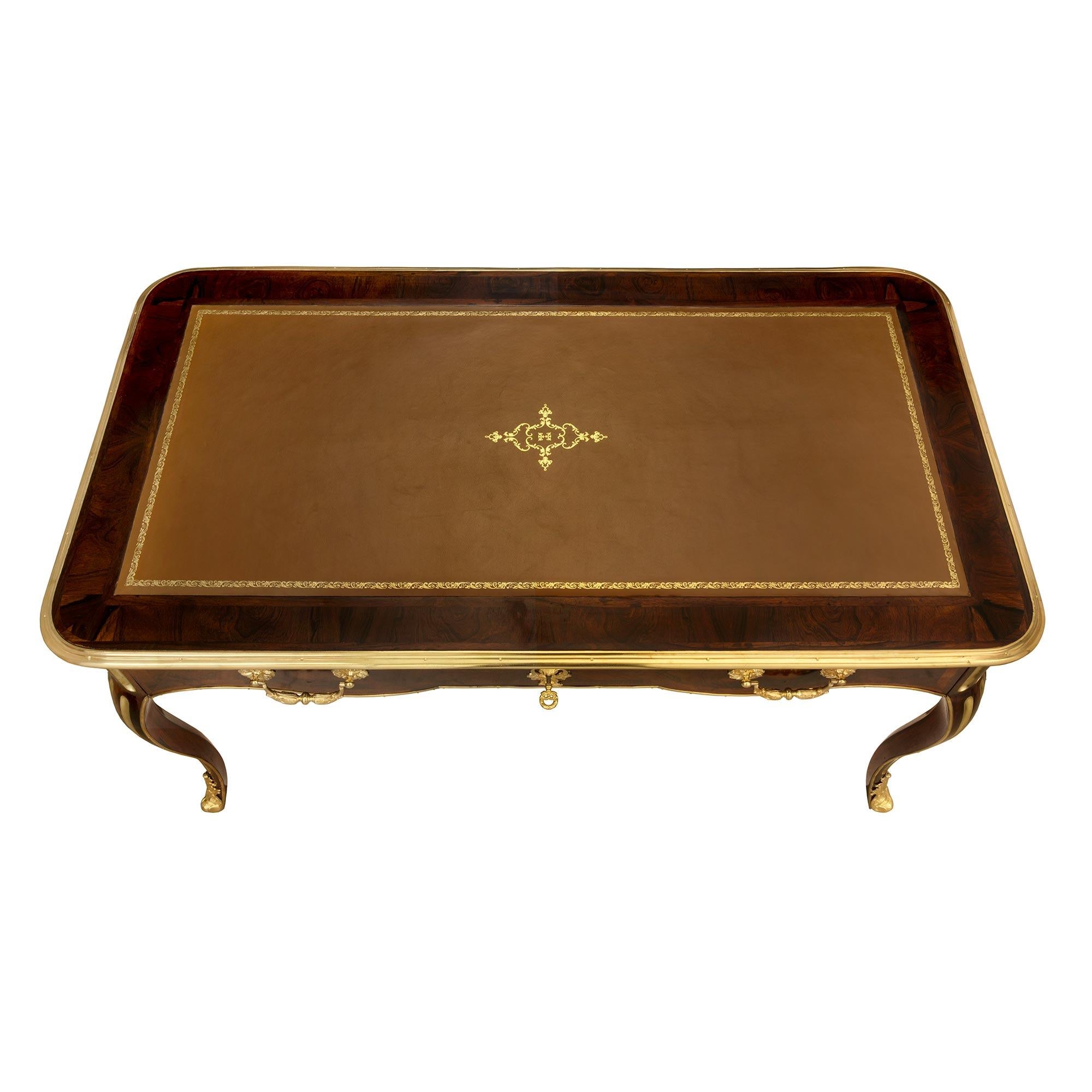 An extremely elegant French 19th century Regence st. rosewood, ormolu and brass desk. The desk is raised by beautiful cabriole legs with most decorative flutes, fitted brass chandelles and fine foliate ormolu sabots. The scalloped shaped frieze